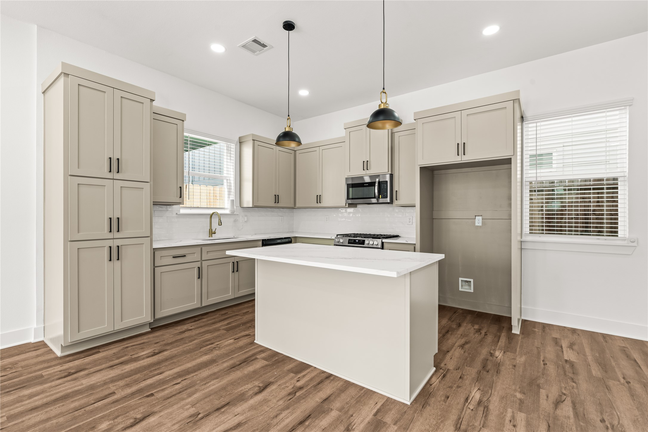 Sophisticated and fully equipped. High-end built-in appliances, a classic subway tile backsplash, and dramatic matte-black and gold pendant lights elevate your daily cooking experience.
