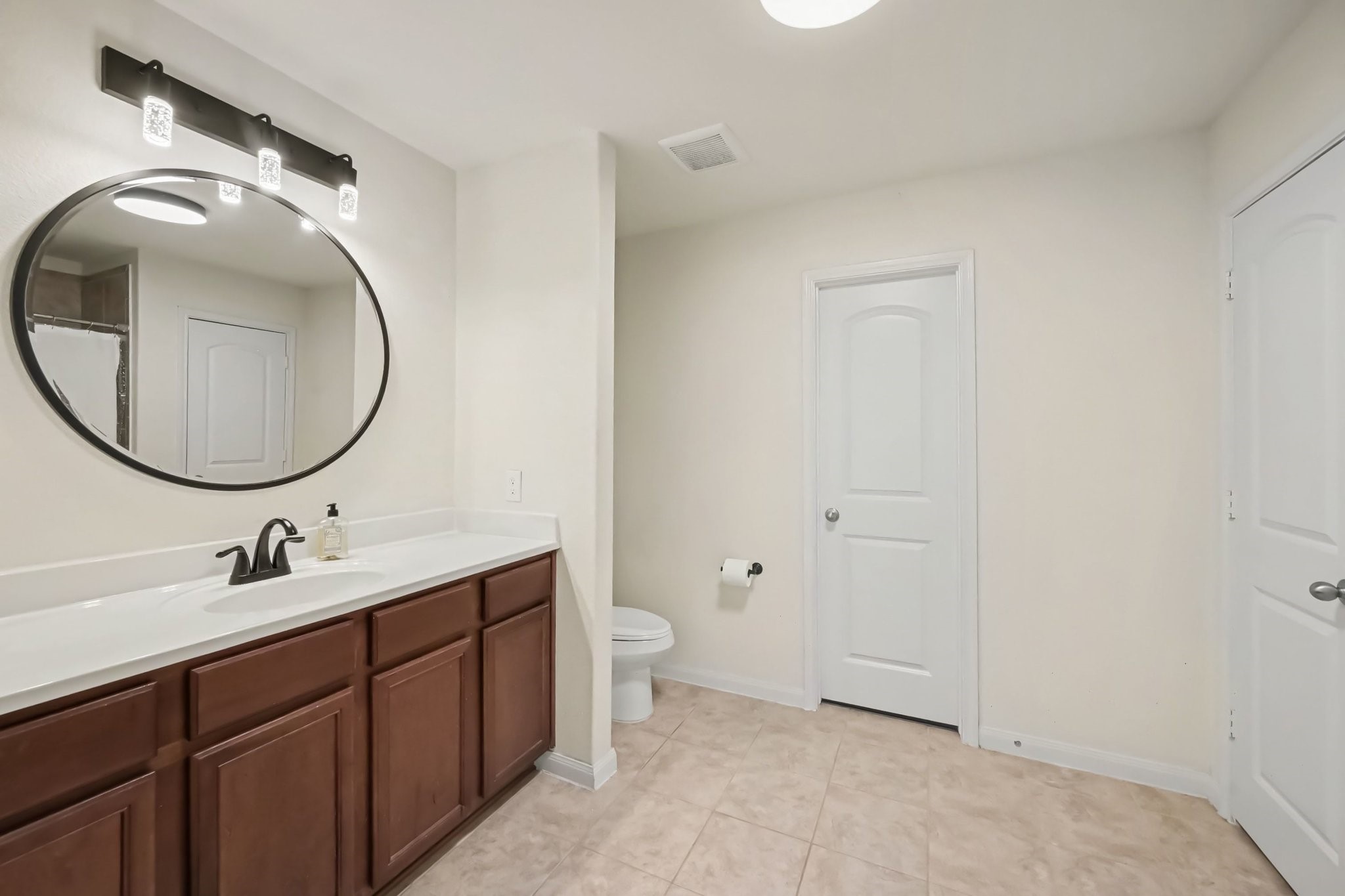 Primary en-suite bathroom with a large single vanity and beautiful updated lighting