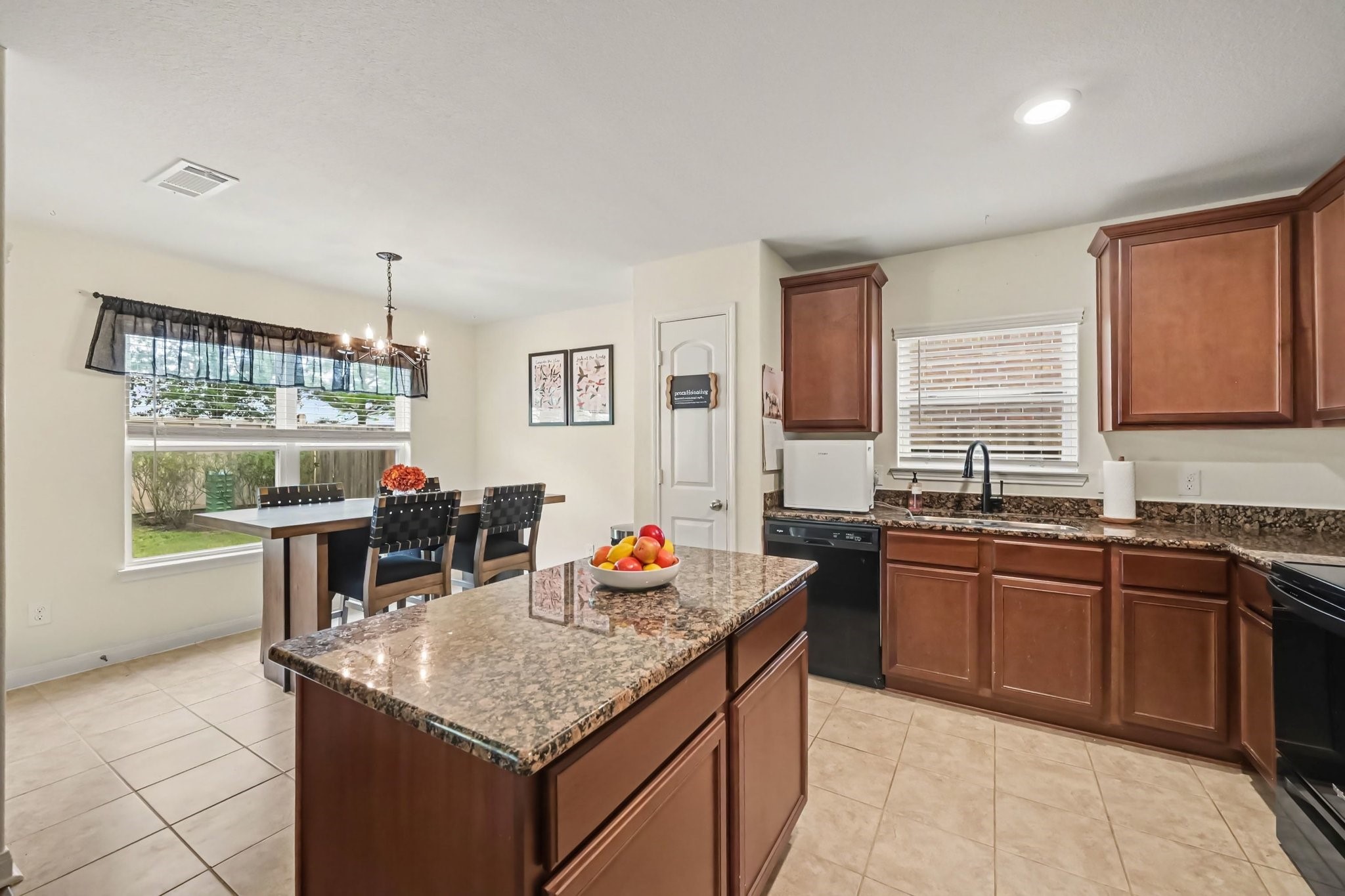 Open kitchen with granite island, dining area, and ceramic tile flooring