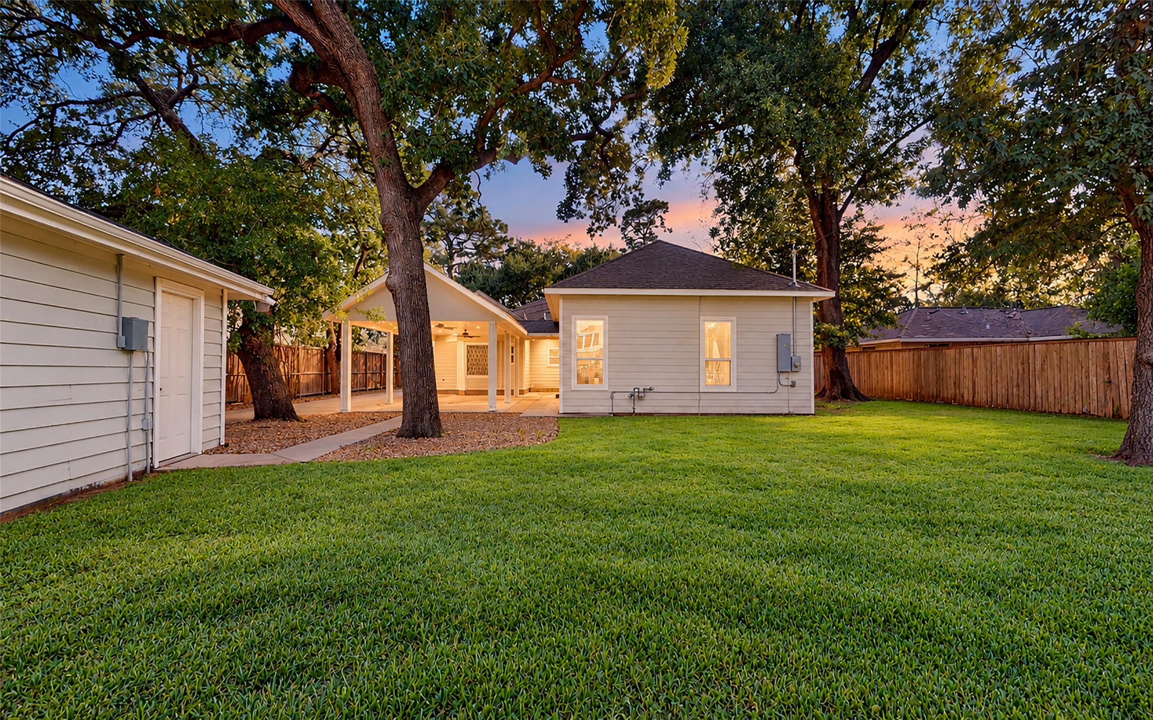 As the sun sets, this beautiful backyard offers a peaceful retreat with towering shade trees, a lush green lawn, plenty of privacy and a covered outdoor area. There's room for backyard games, weekend gatherings or simply enjoying a quiet evening at home, while a full sprinkler system helps keep the lawn and landscaping looking their best.