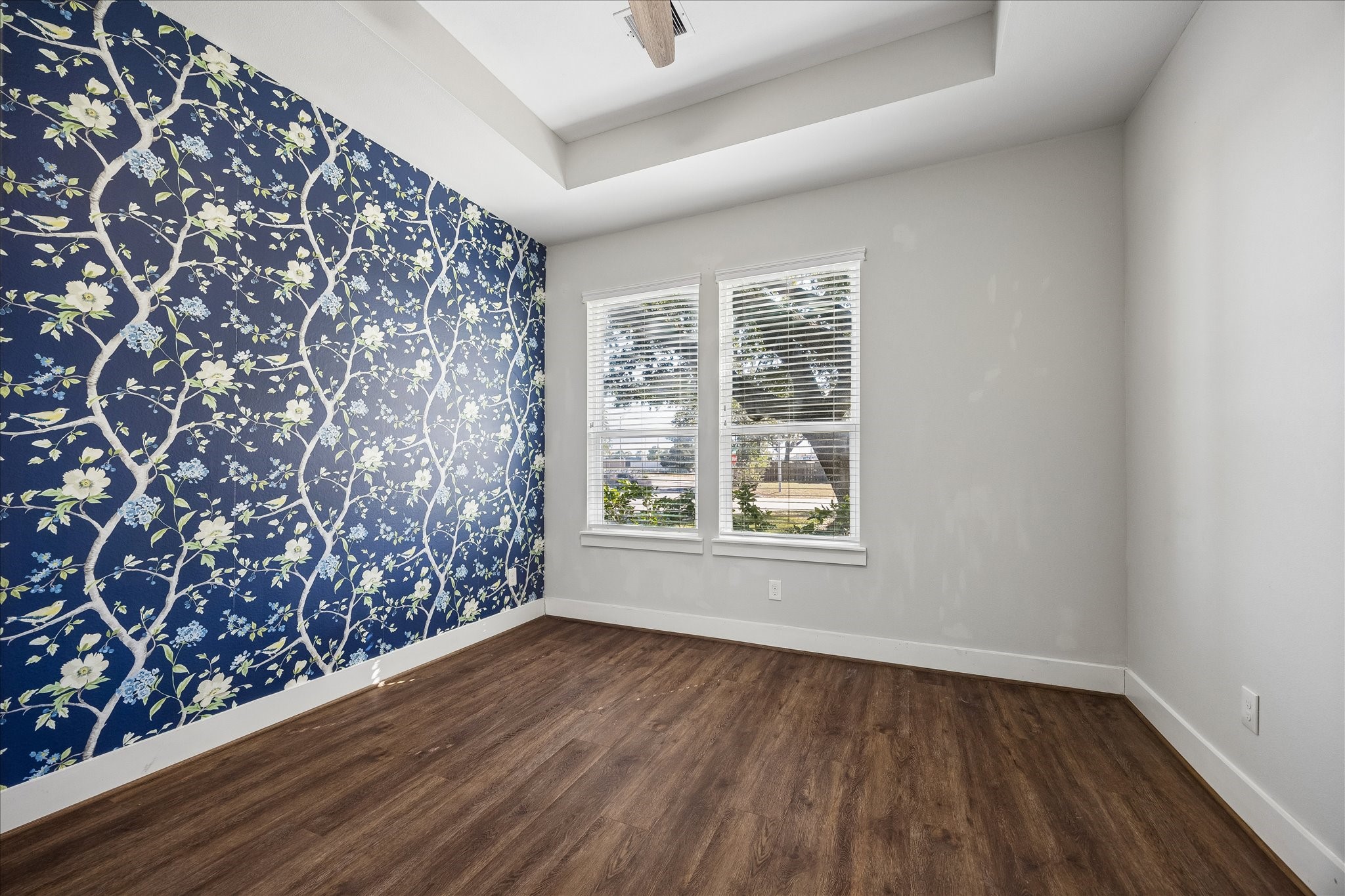 Who says a guest bedroom can't have a little personality? Gorgeous custom wallpaper creates a beautiful accent wall, while a tray ceiling, large windows and updated luxury vinyl tile flooring make this a bright, inviting retreat.