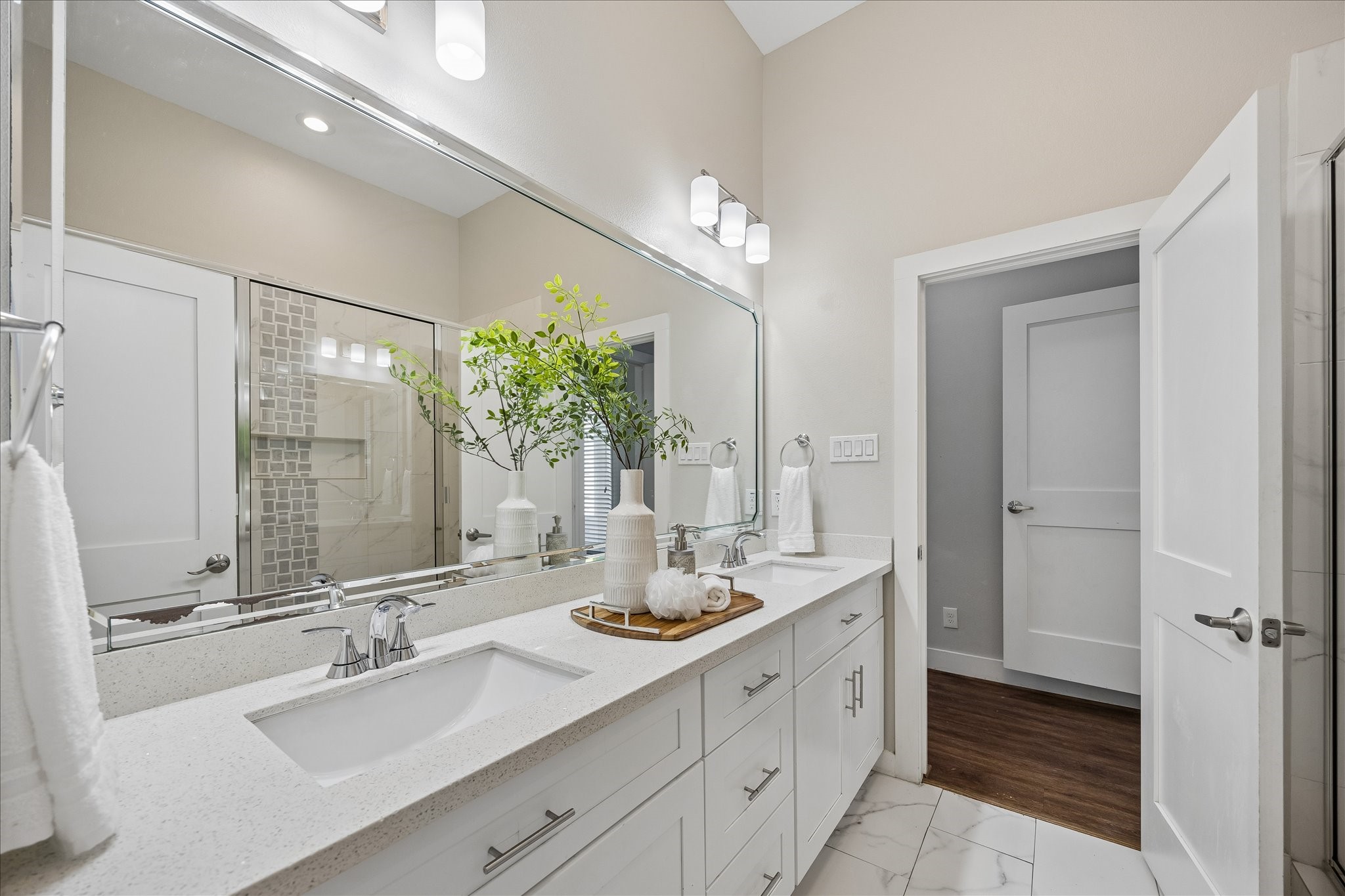 No need to compete for mirror space here. Dual sinks, an expansive vanity, stylish lighting and abundant cabinetry give everyone room to get ready, while the soft neutral finishes create a bright, relaxing atmosphere.