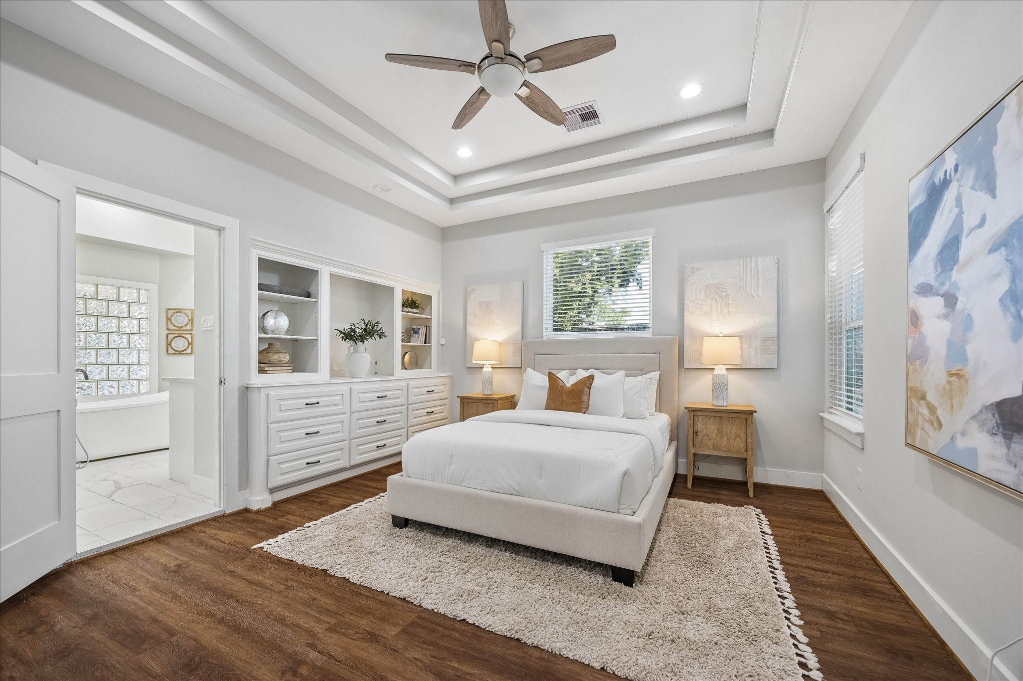 Your own private retreat awaits. This luxurious primary suite offers a beautiful triple tray ceiling, custom built-ins and updated luxury vinyl tile flooring. With extensive closet space and a spa-like ensuite just steps away, you'll love having a peaceful place to escape, recharge and enjoy a little well-deserved downtime.