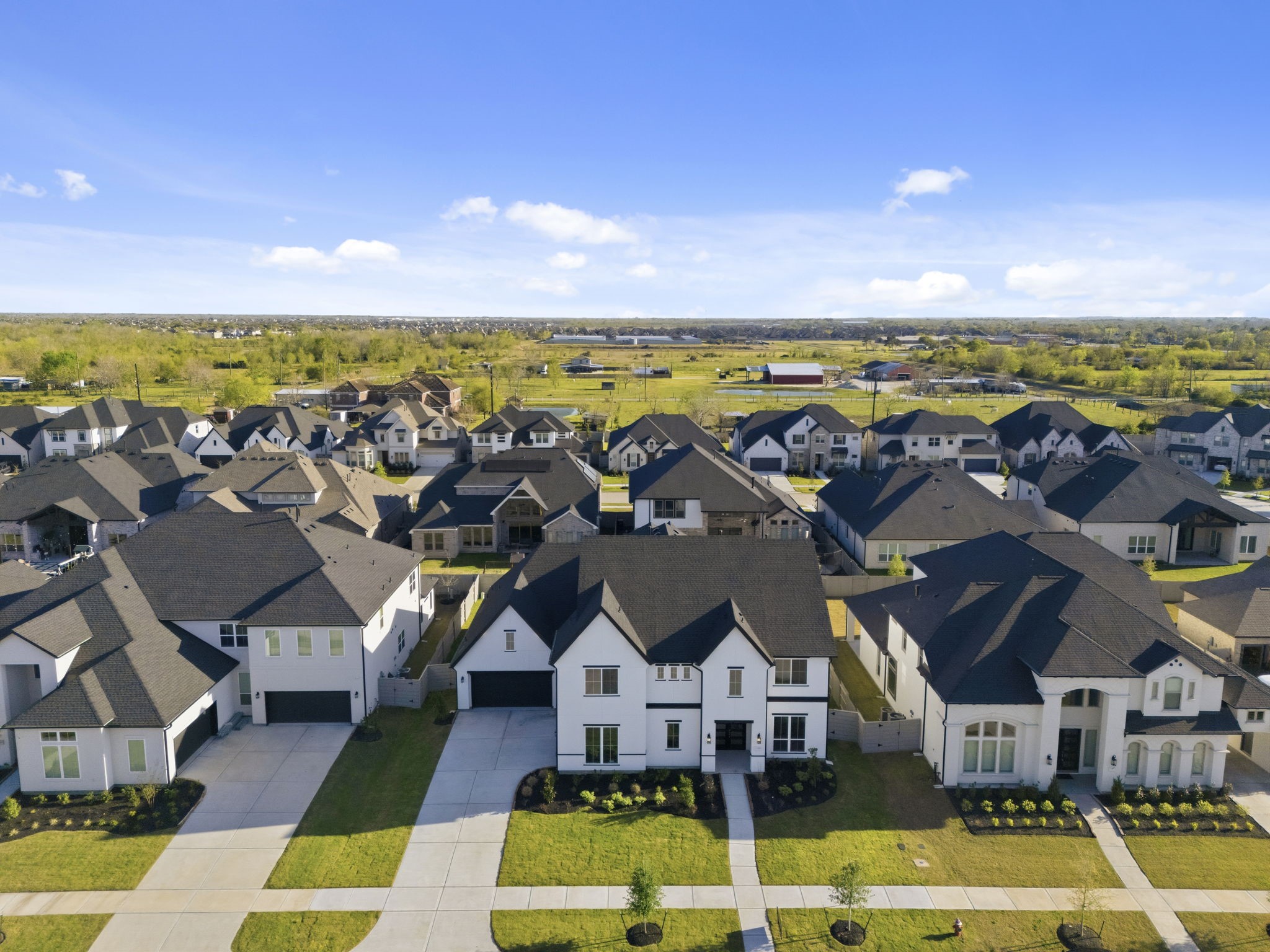 Modern suburban neighborhood with spacious, stylish homes featuring well-maintained lawns. The area is open and airy, offering a sense of community with easy access to green spaces.