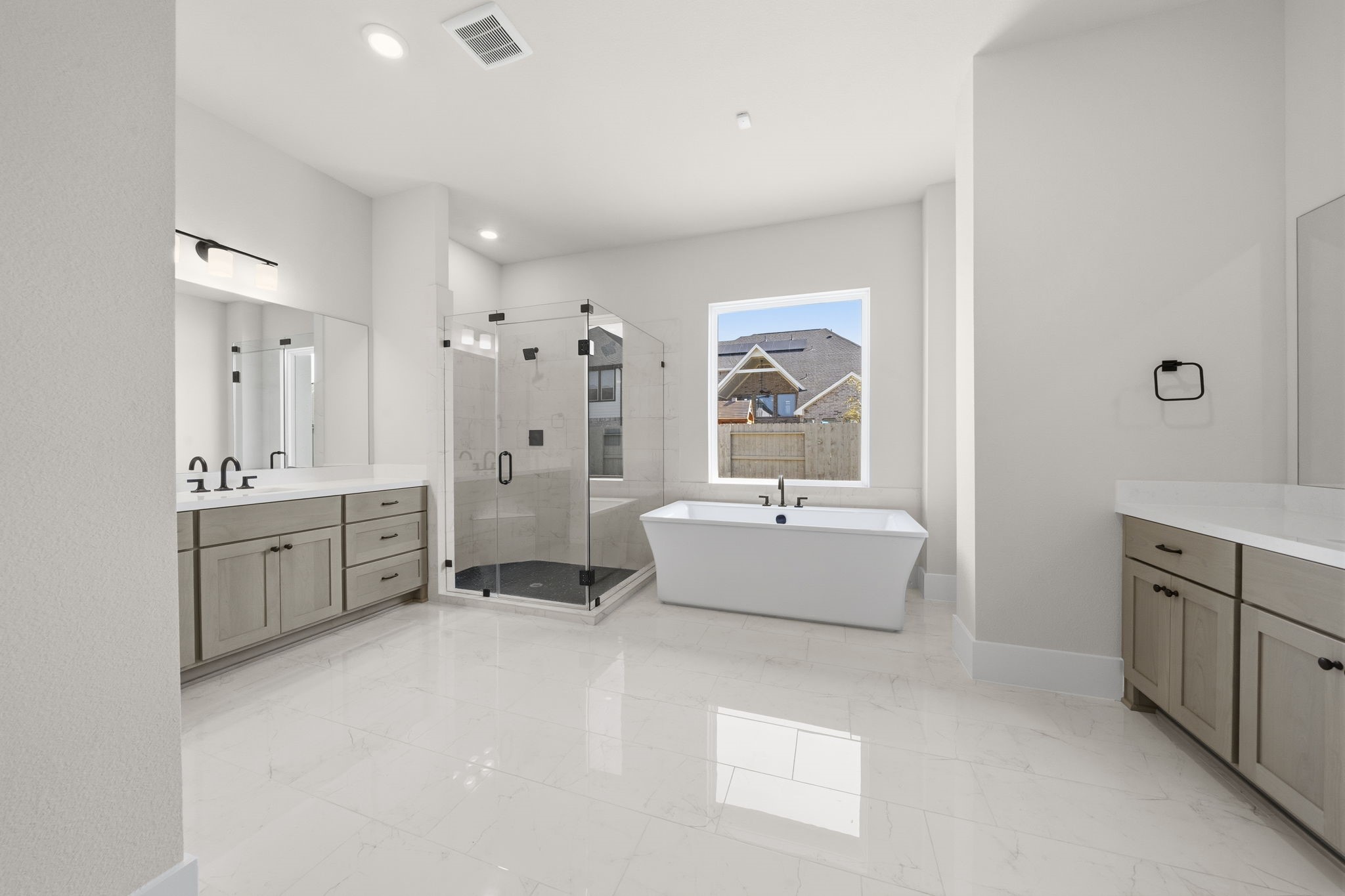 Home Spa, spacious, modern bathroom features a freestanding tub, an elegant glass-enclosed shower, dual vanities with ample storage, and large windows for natural light.