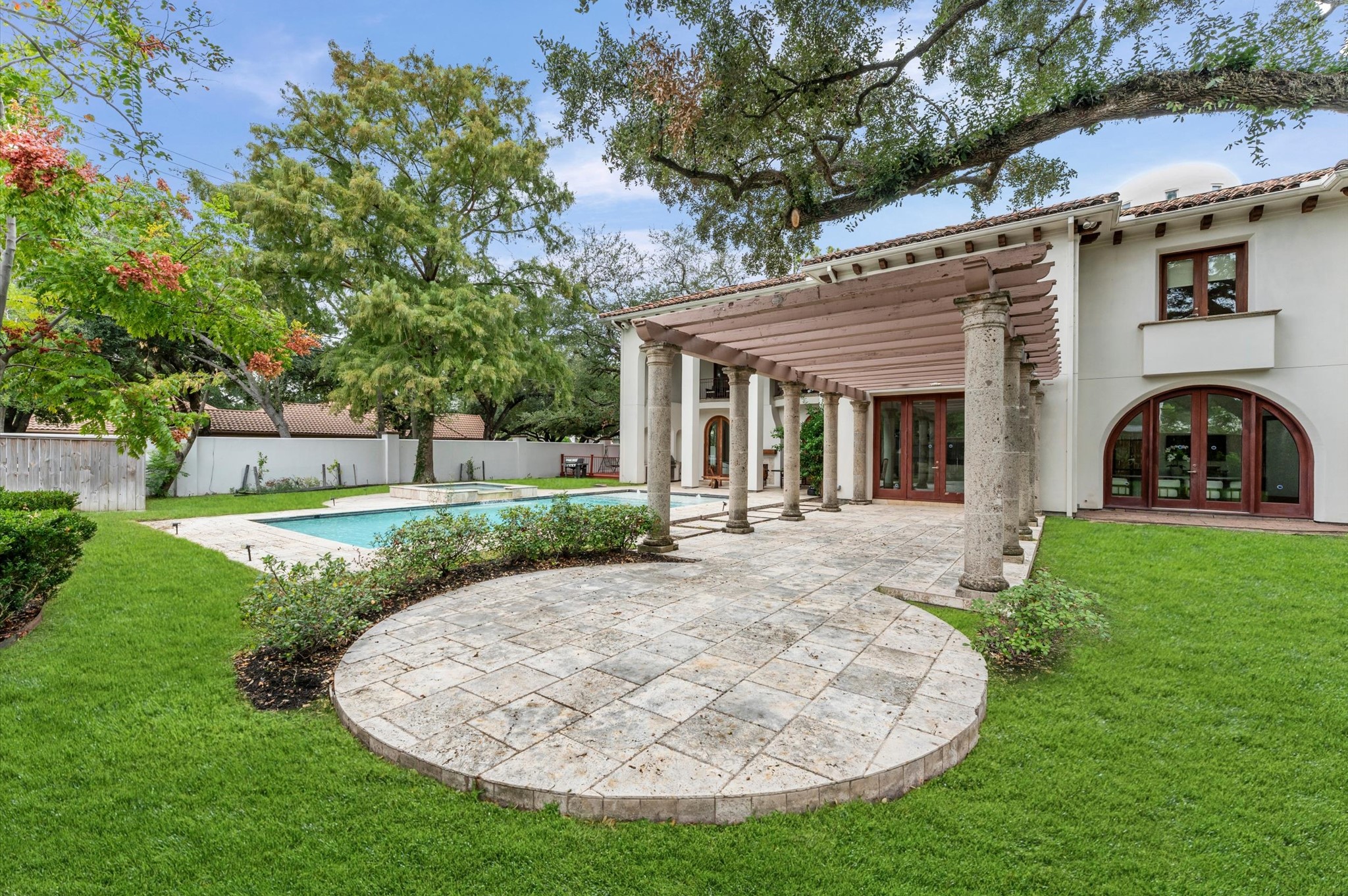 A private patio tucked at the end of the pergola offers an additional outdoor seating or dining destination surrounded by the estate's landscaped grounds.