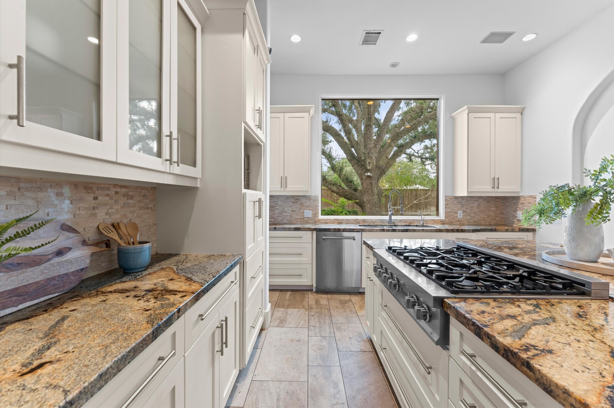 Alternate kitchen view featuring an expansive island with breakfast bar, built-in wall ovens, double-basin sink, granite countertops, and freshly painted cabinetry.