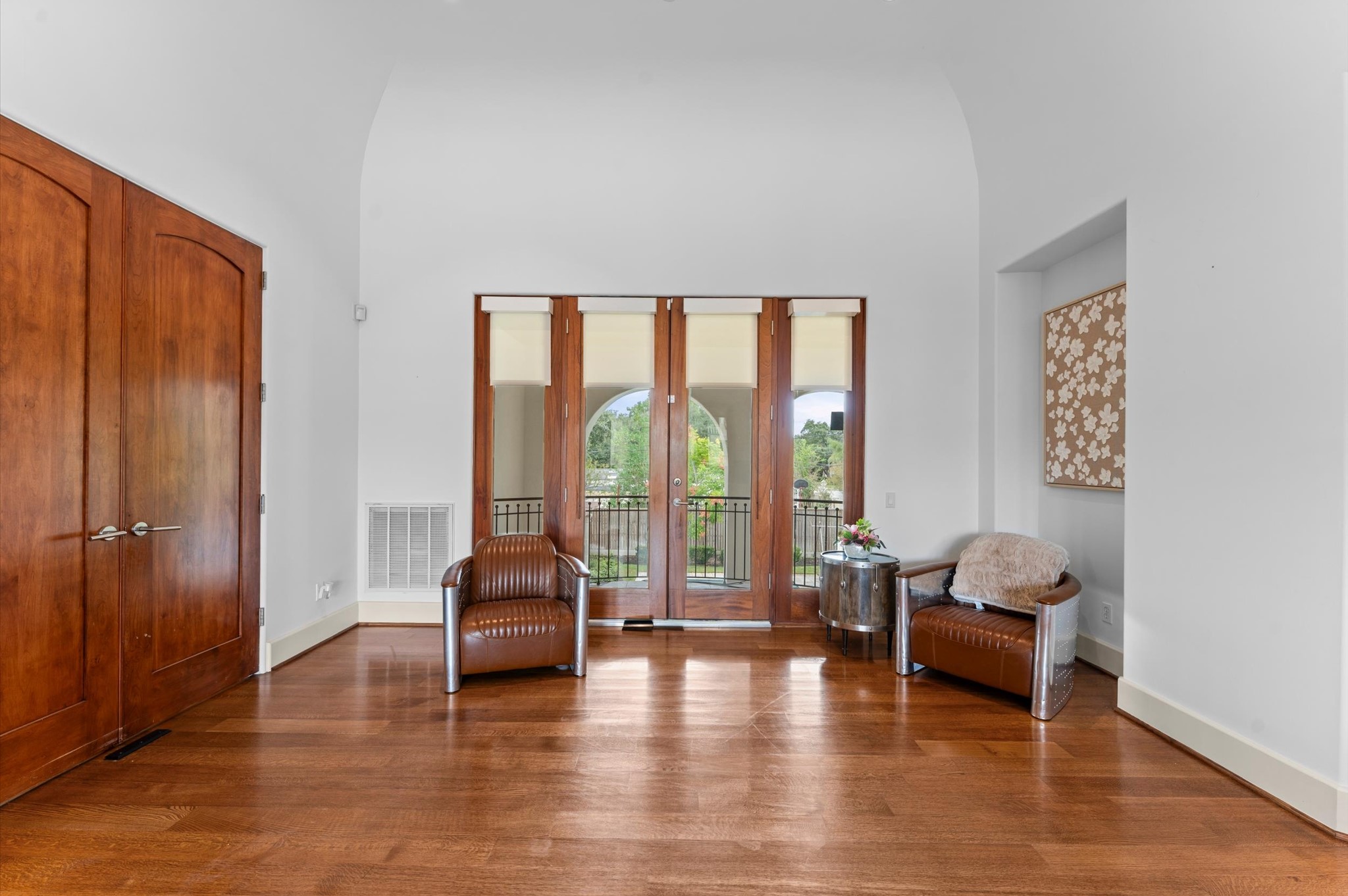 Solid mahogany doors open to a secluded primary suite in its own private wing, featuring an inviting sitting area and a private balcony overlooking the pool.