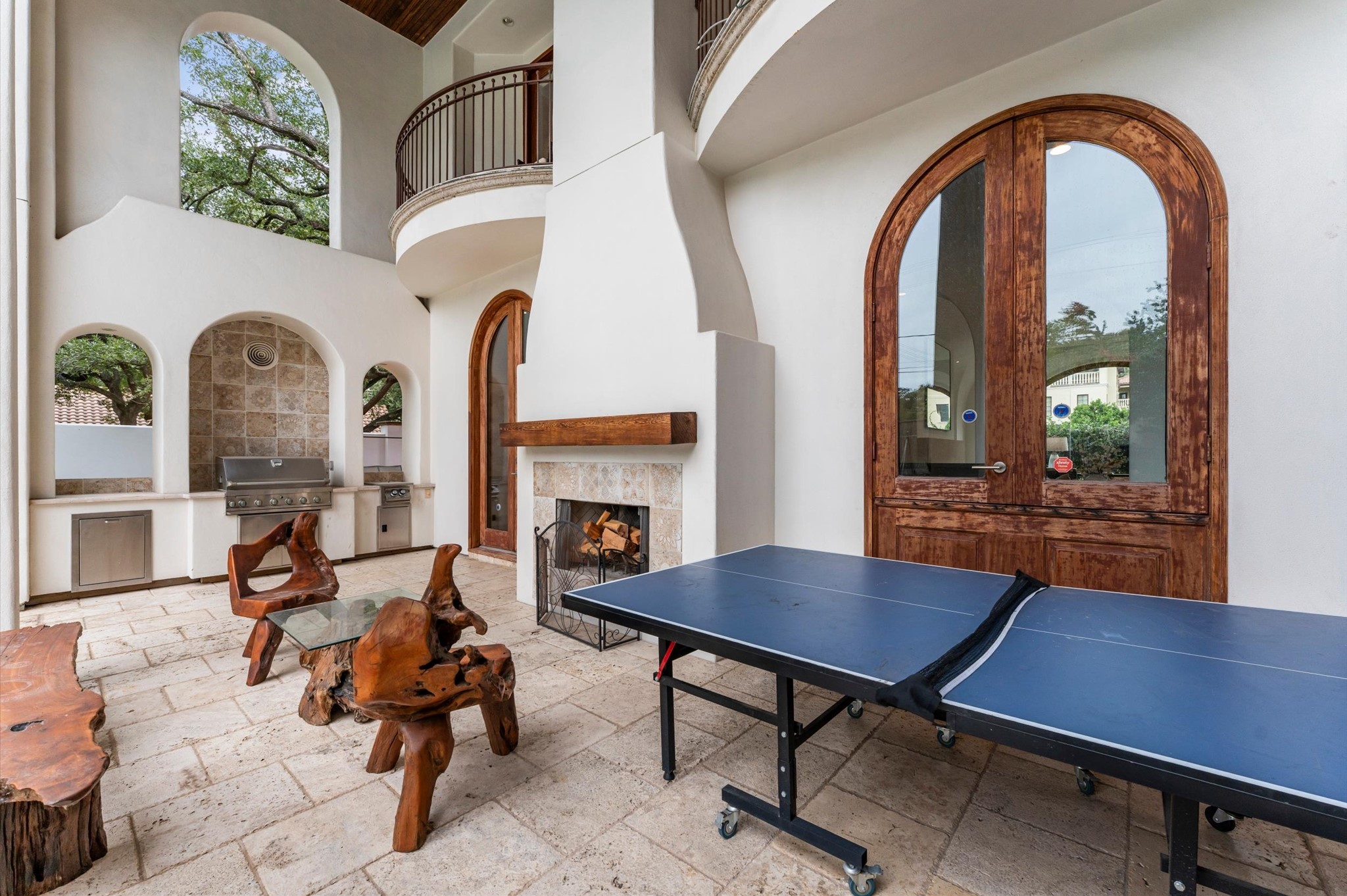 The covered rear loggia creates an inviting outdoor living room, complete with a raised fireplace, built-in gas grill, and separate burner, ideal for year-round entertaining.