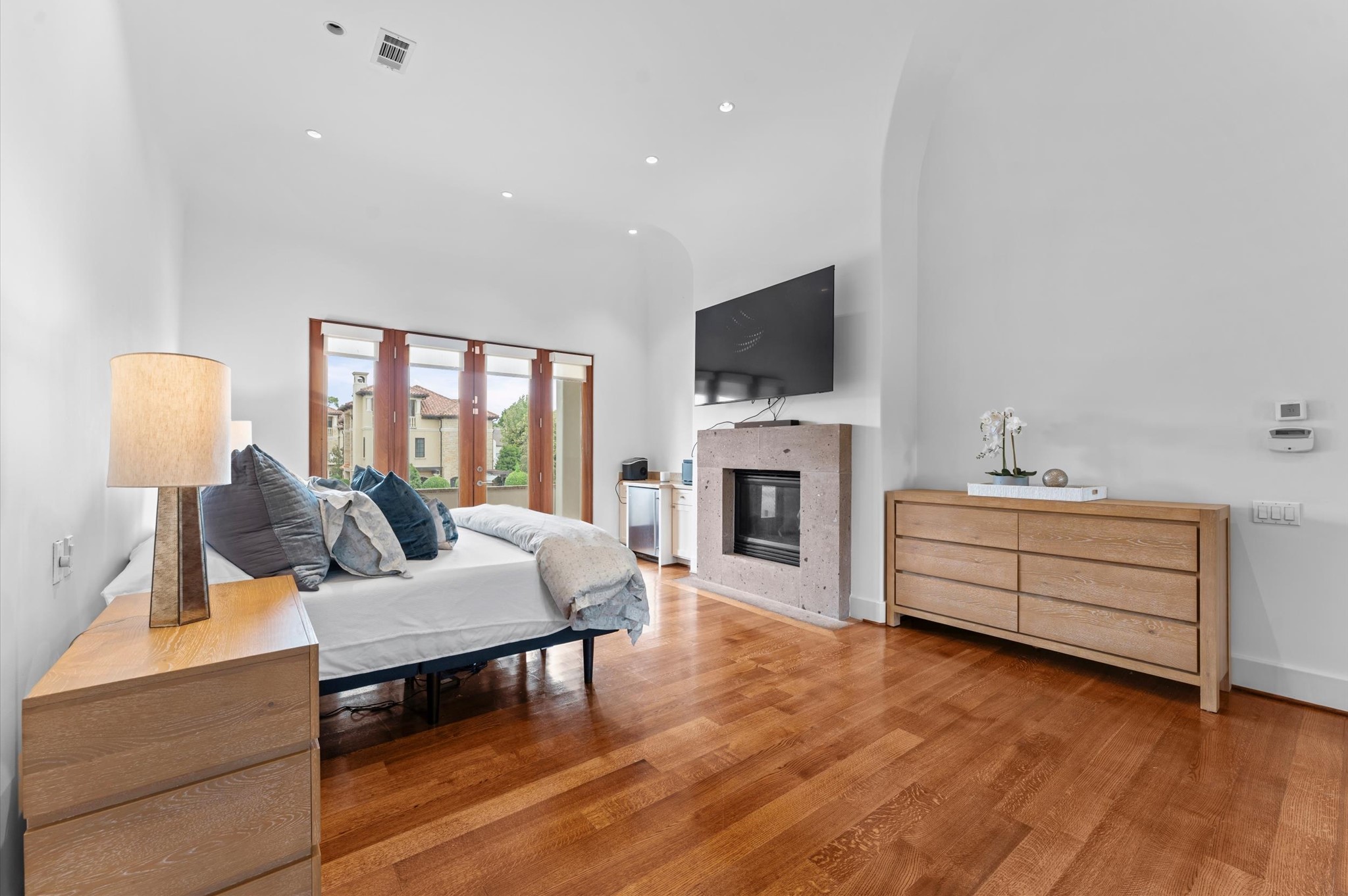 An expansive primary retreat featuring a stone fireplace, a convenient morning bar, and multiple balconies, creating a luxurious private escape with seamless indoor-outdoor living.