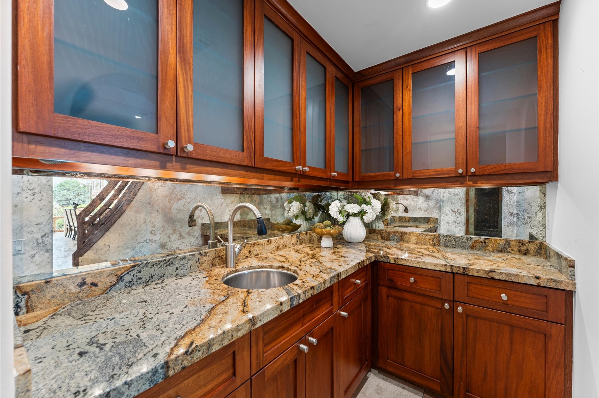 A full-service butler's pantry off the kitchen offers extensive storage, custom mahogany cabinetry, granite countertops, and a dedicated sink, providing an elegant and functional extension of the gourmet kitchen.