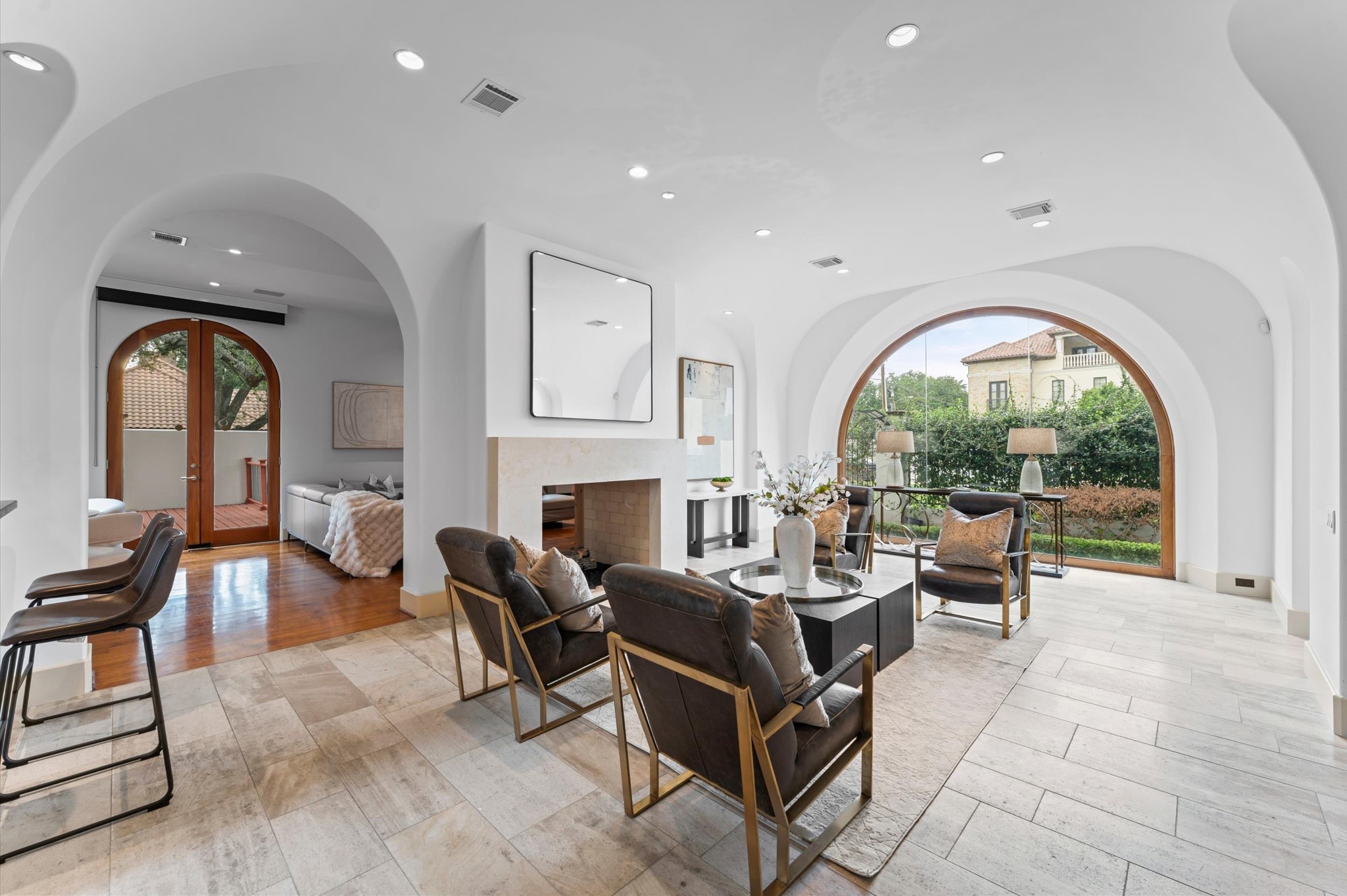 The expansive reception gallery flows seamlessly into the double living room, unified by a shared stone fireplace and elegant imported travertine flooring.