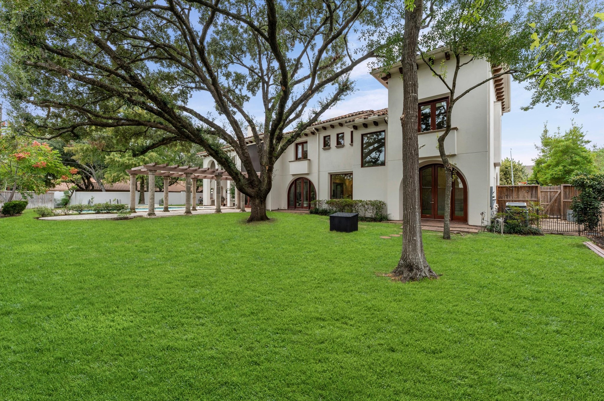 Enjoy the beauty and privacy of expansive grounds framed by mature trees, manicured lawns, and timeless Modern Spanish architecture. The generous backyard offers a stunning setting for outdoor living, with the resort-style pool, grand pergola, and elegant arched windows completing this exceptional estate.