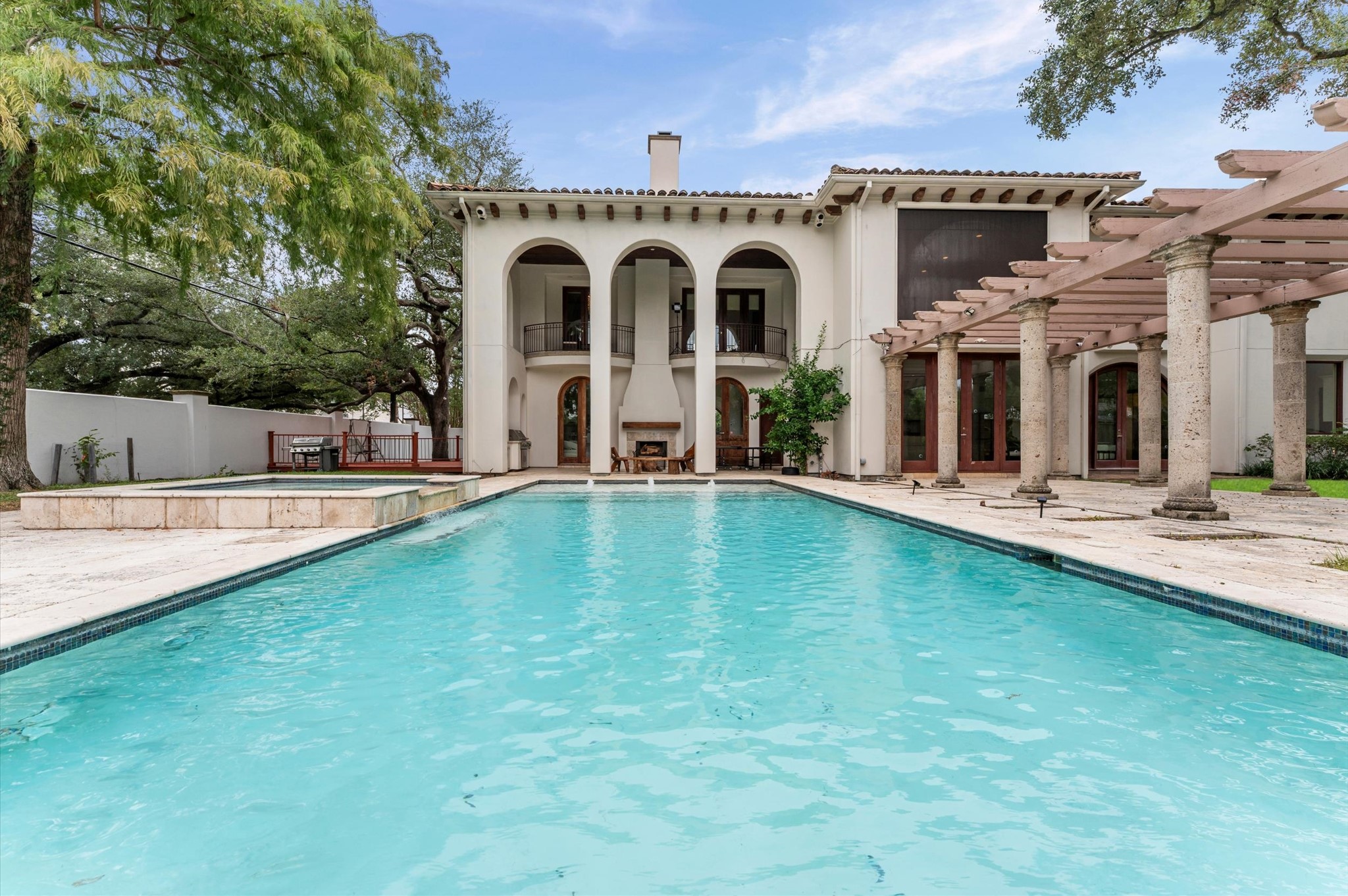 A custom-designed saltwater pool and raised spa anchor the expansive outdoor oasis, complemented by water features, ambient lighting, dedicated outdoor dining areas, an outdoor bathroom, fireplace, and mosquito control system.