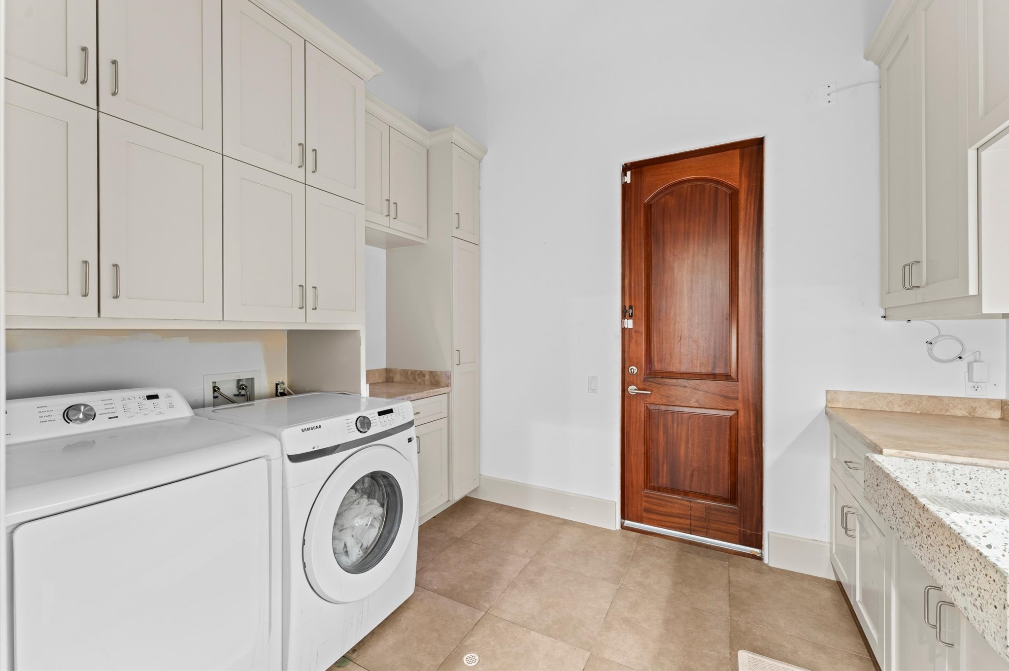 A spacious laundry room with custom built-in cabinetry and convenient exterior access to the side patio near the garage, combining functionality with everyday convenience.
