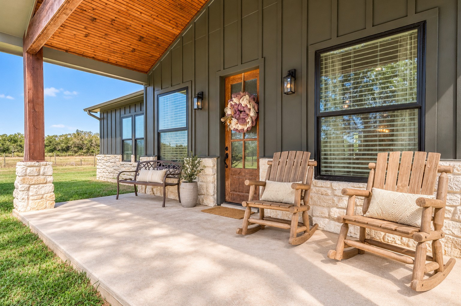 Covered front porch with cedar posts, stone wainscot and room for rocking chairs, overlooking the front pasture. This photo may be edited using AI tools.