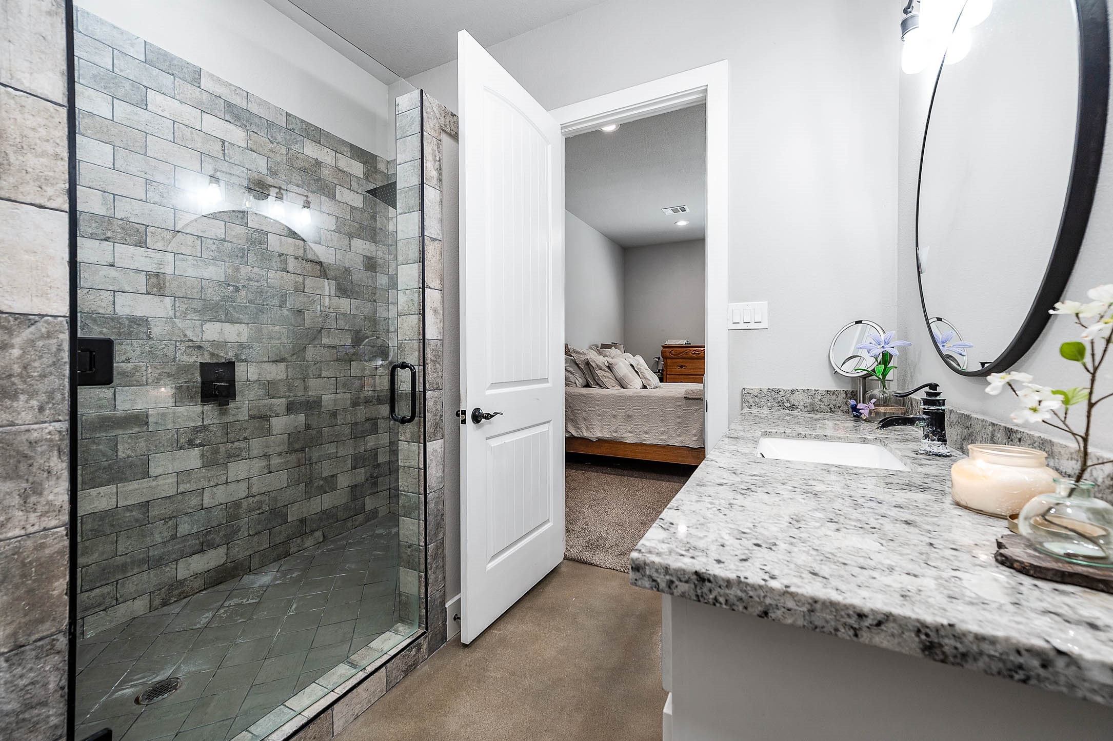 Primary bathroom walk-in shower with tile surround and frameless glass door. This photo may be edited using AI tools.