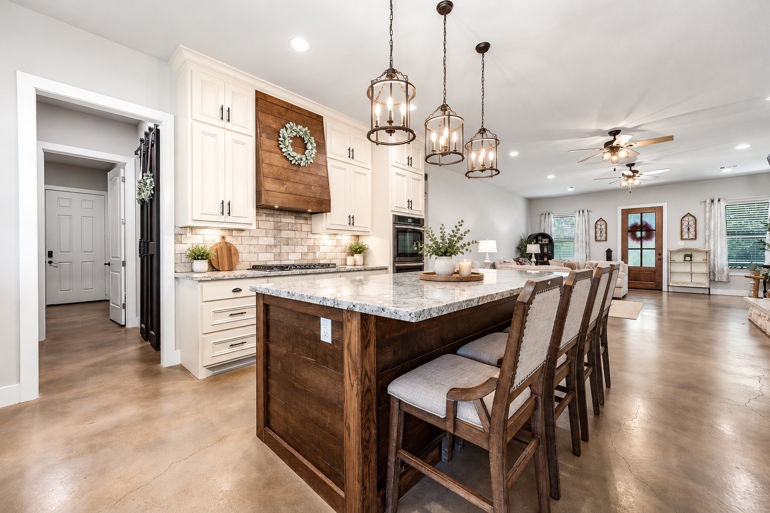 Kitchen island with granite countertops, bar seating and pendant lights, open to the dining and family rooms. This photo may be edited using AI tools.