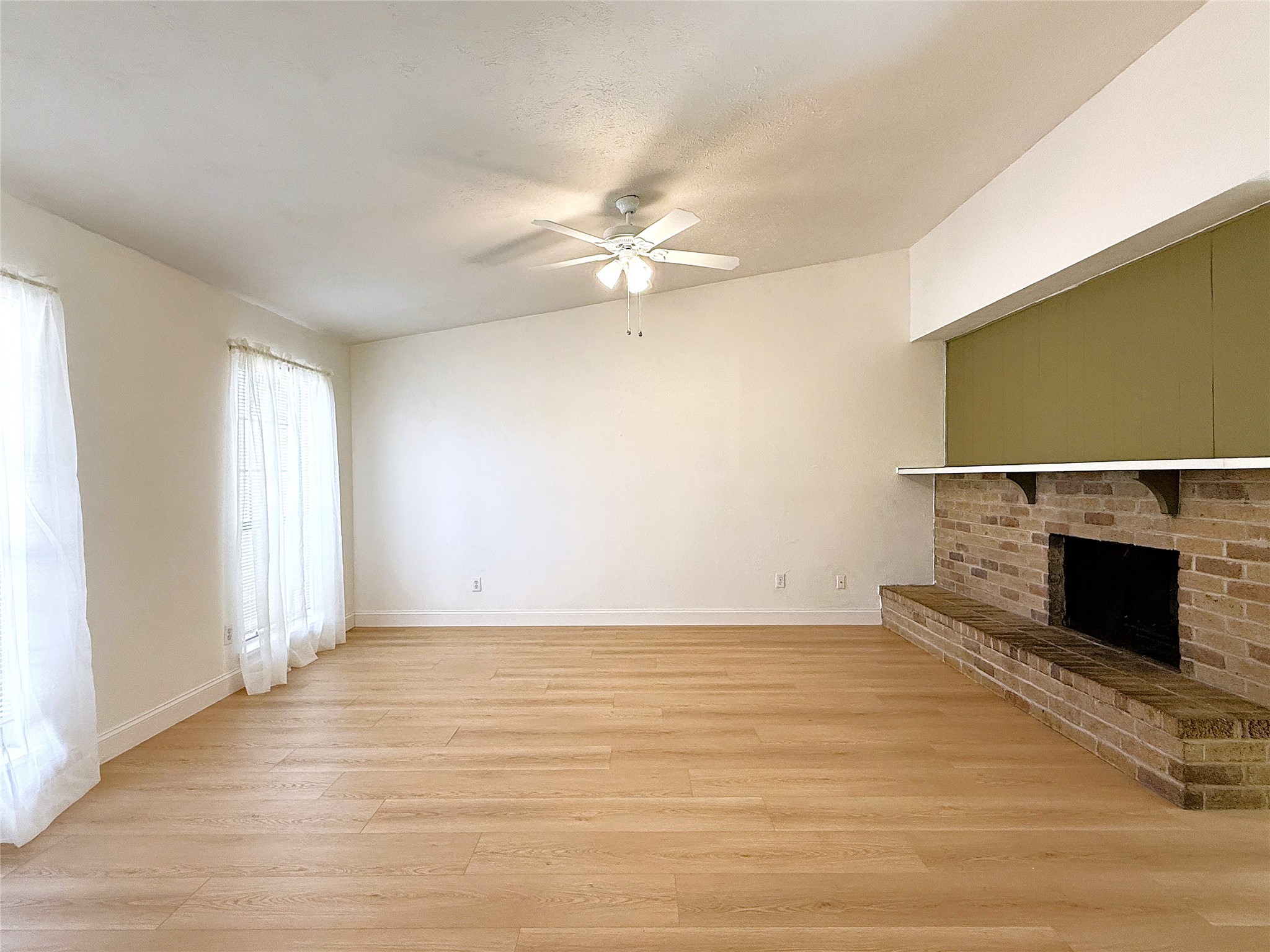 Spacious living with woodburning fireplace and laminate flooring.