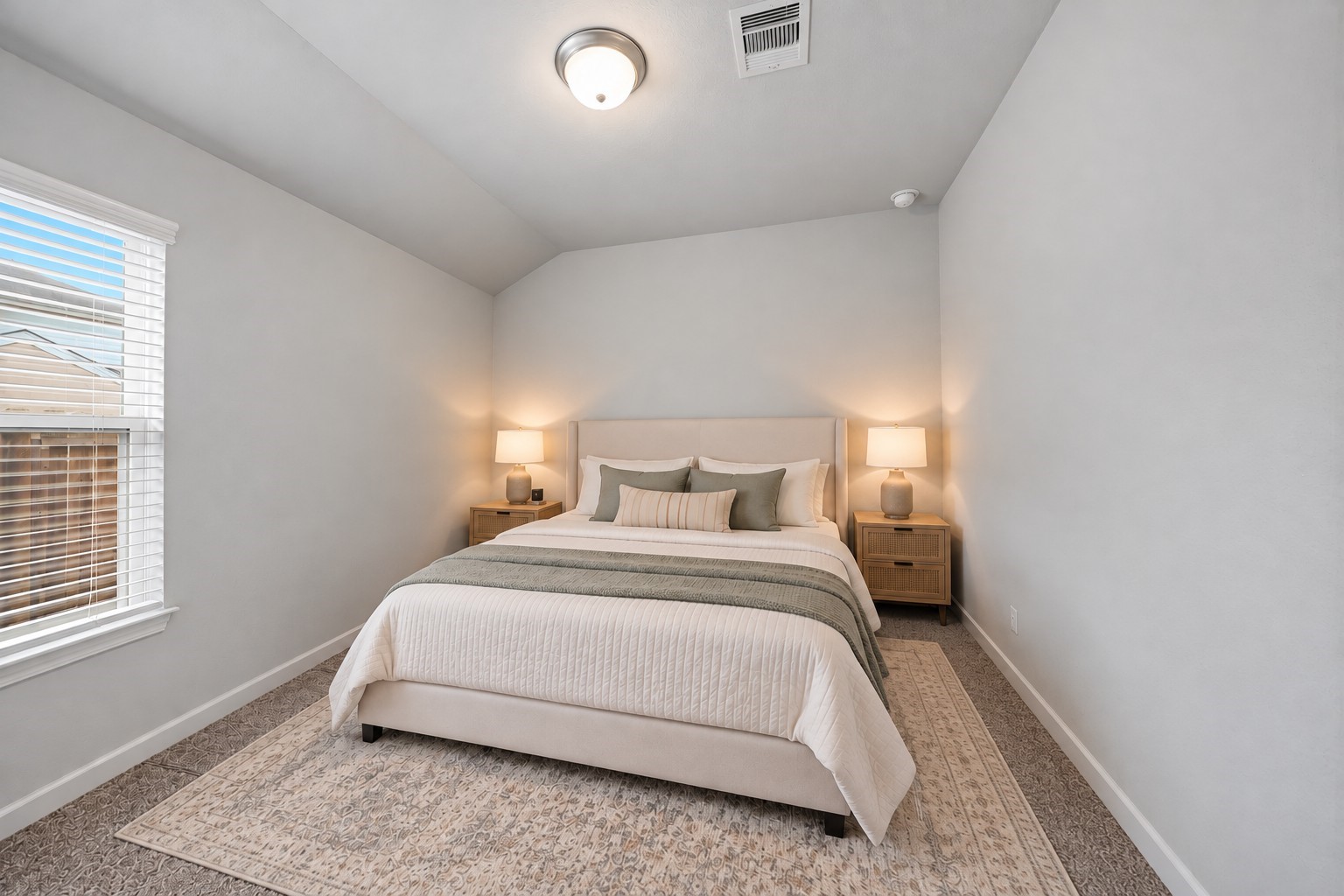 Virtually Staged: This inviting secondary bedroom features a vaulted ceiling, soft neutral walls, and plush carpeting that creates a comfortable, welcoming atmosphere. A large window allows abundant natural light to brighten the space.
