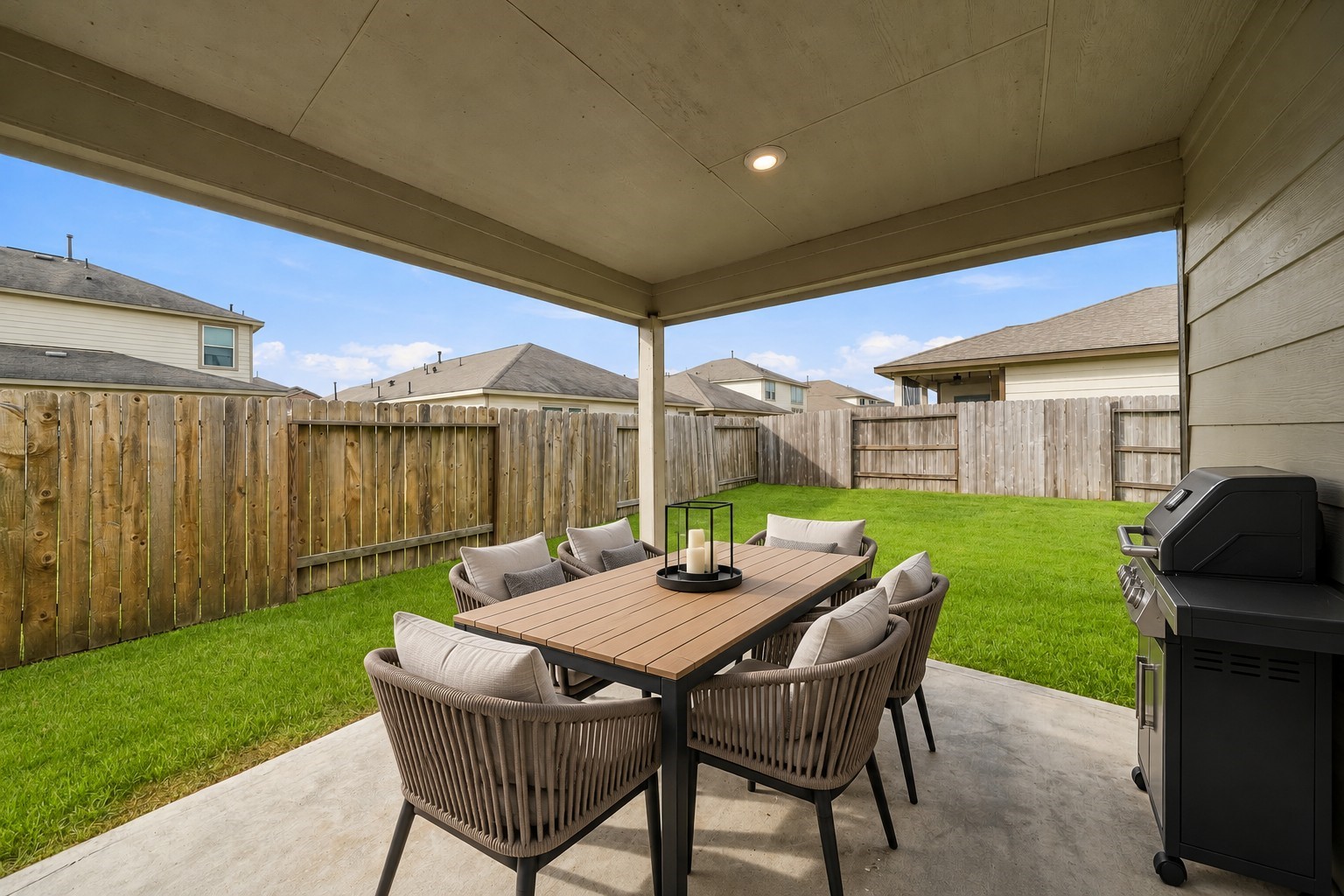 From this vantage point, you have a beautiful view of an expansive, lush green grass backyard, bordered by a wooden fence providing more privacy.