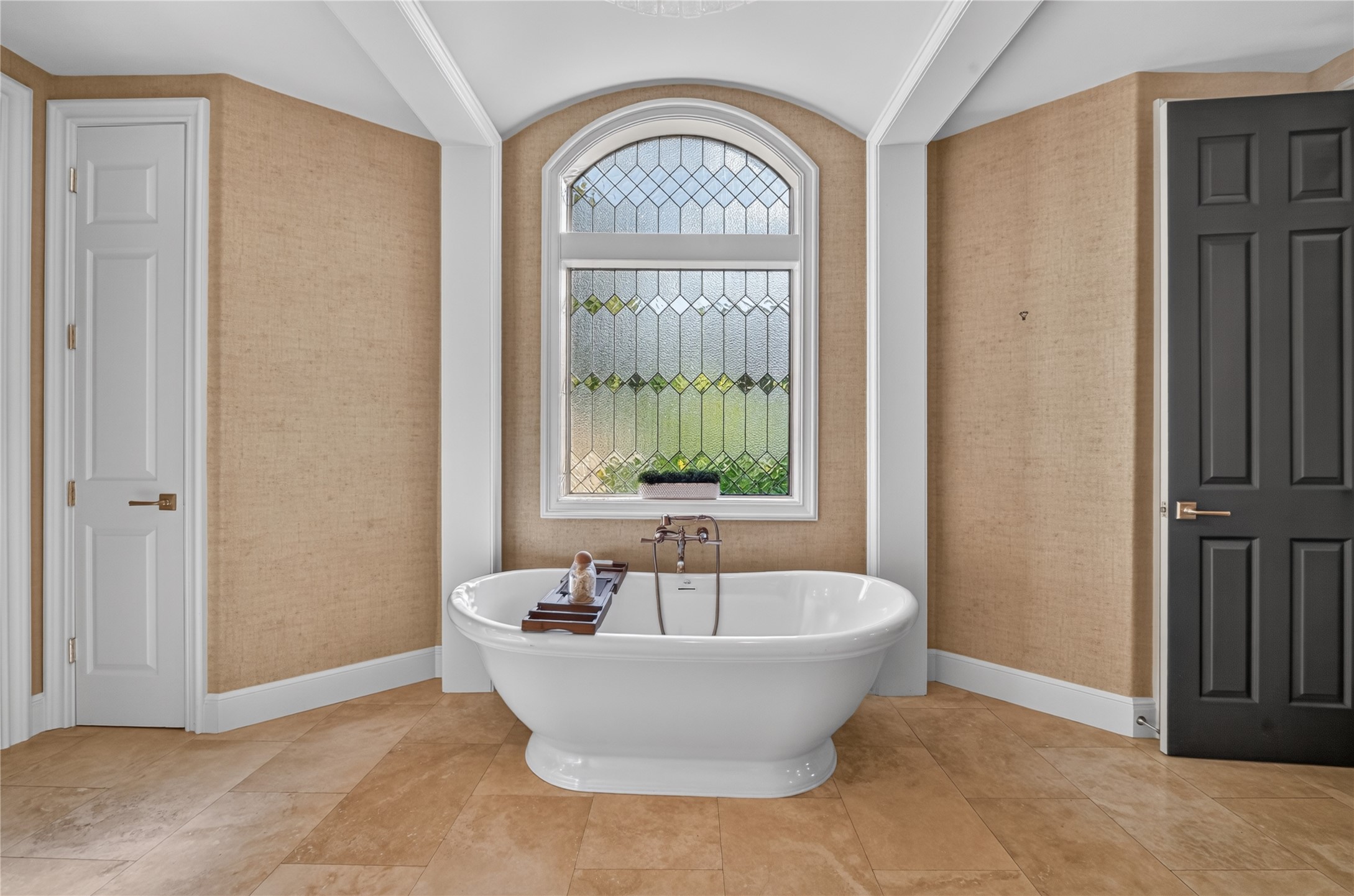Simple yet sophisticated leaded glass window hangs above the soaking tub.