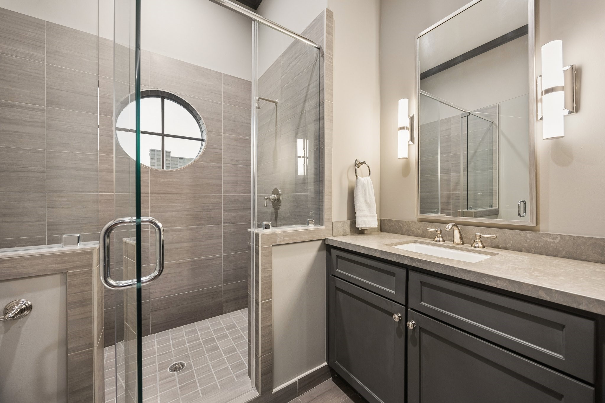 Elegant fourth-floor full bathroom featuring a glass-enclosed walk-in shower, contemporary tilework, stone countertop, and a custom vanity. Conveniently located adjacent to the spacious game room, offering flexibility for use as a private guest suite.