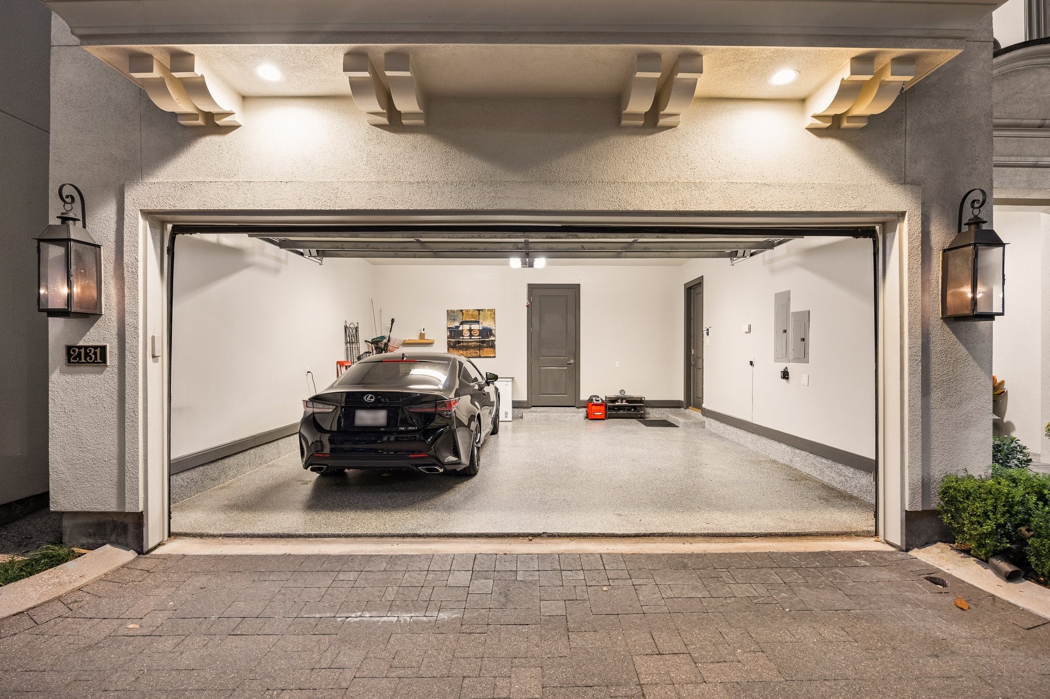Spacious two-car garage featuring high ceilings, durable epoxy flooring, and additional storage in a separate walk-in storage room.