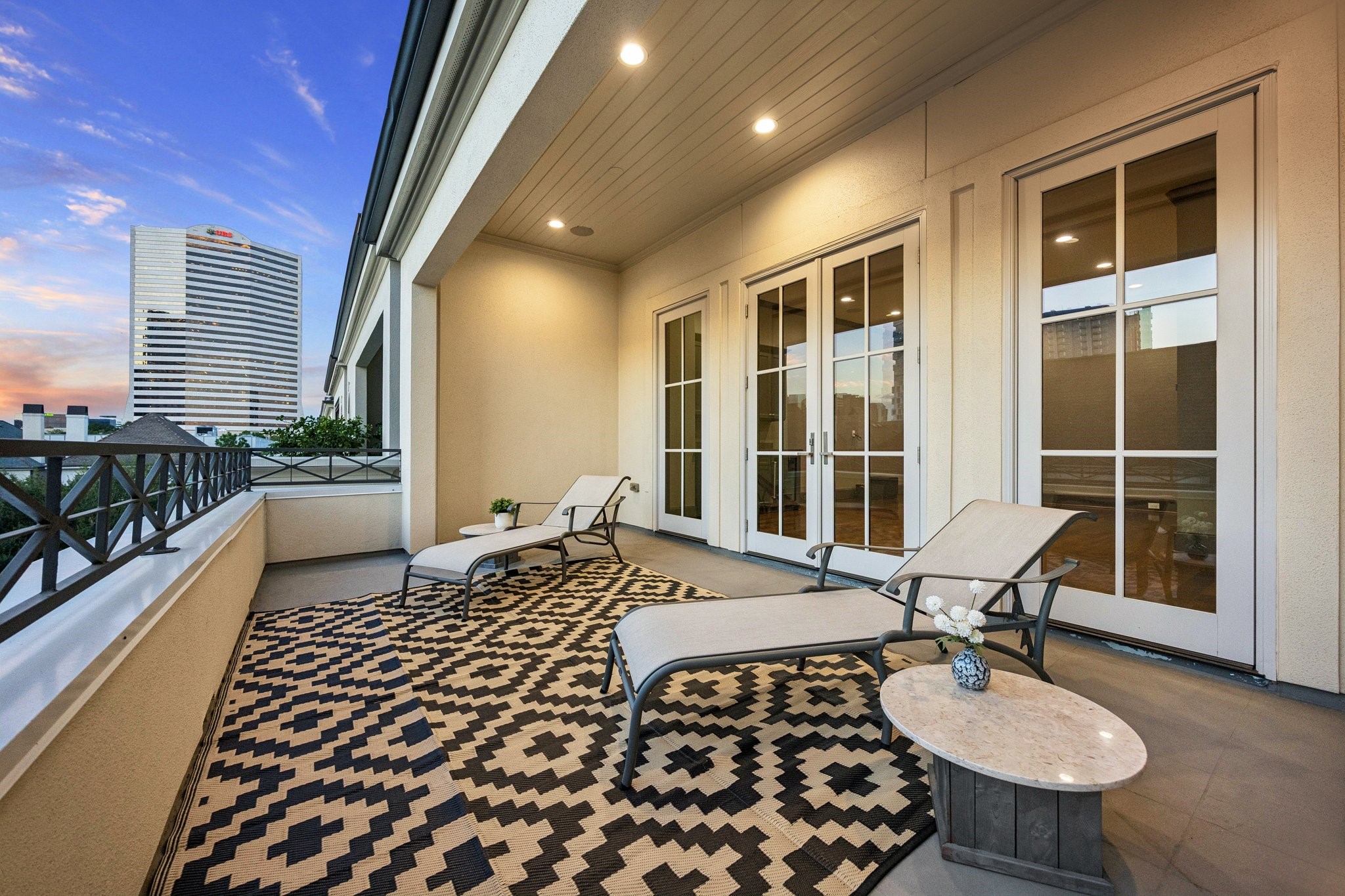 Spacious fourth-floor covered terrace featuring motorized retractable screens, multiple French doors, ample room for outdoor lounging, and skyline viewsperfect for relaxing or entertaining.