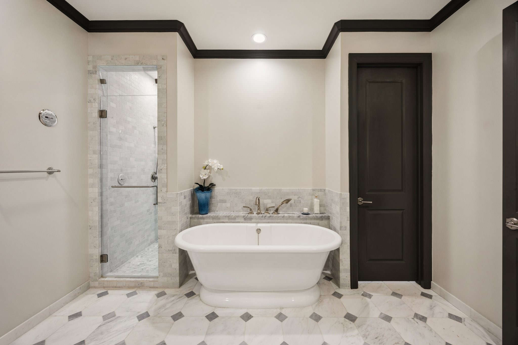 Luxurious primary bathroom featuring a Victoria + Albert freestanding soaking tub, glass-enclosed steam shower, and exquisite marble flooring with decorative stone inlays.