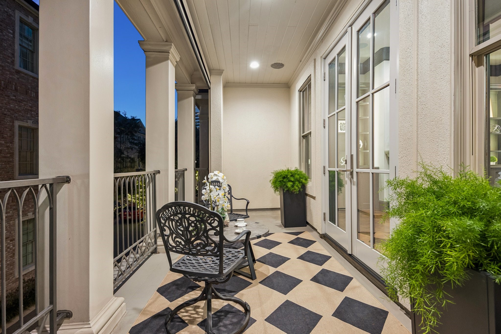 Spacious covered balcony off the formal living room, featuring elegant columns, decorative railings, and ample room for outdoor seatingperfect for morning coffee or evening relaxation.