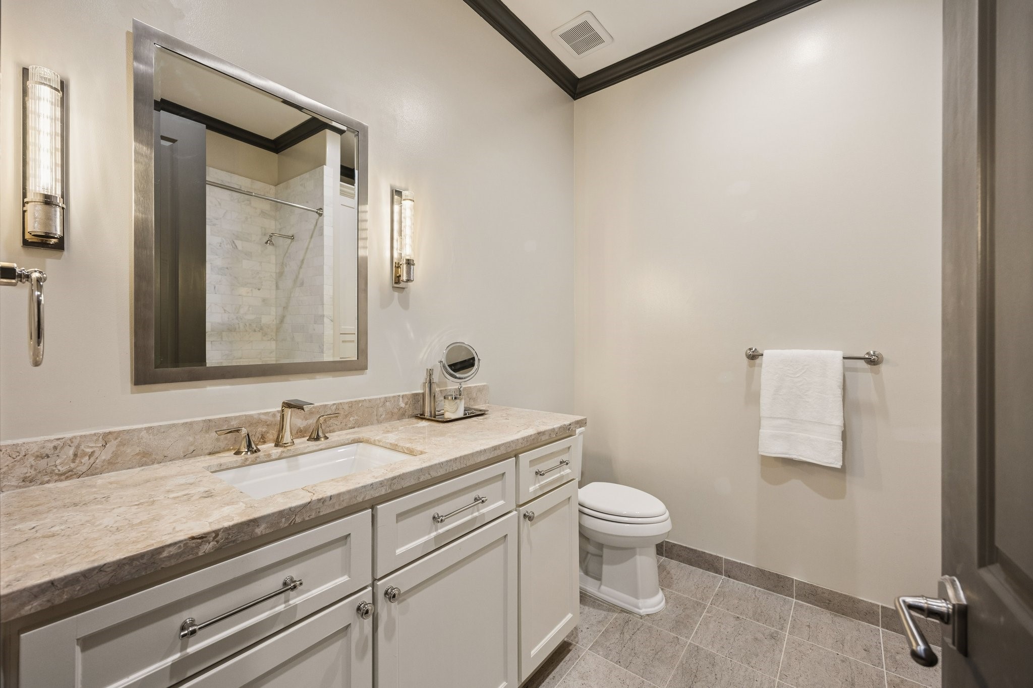 Elegant first-floor en-suite bathroom featuring a stone countertop, custom vanity, and a beautifully tiled tub and shower combination.
