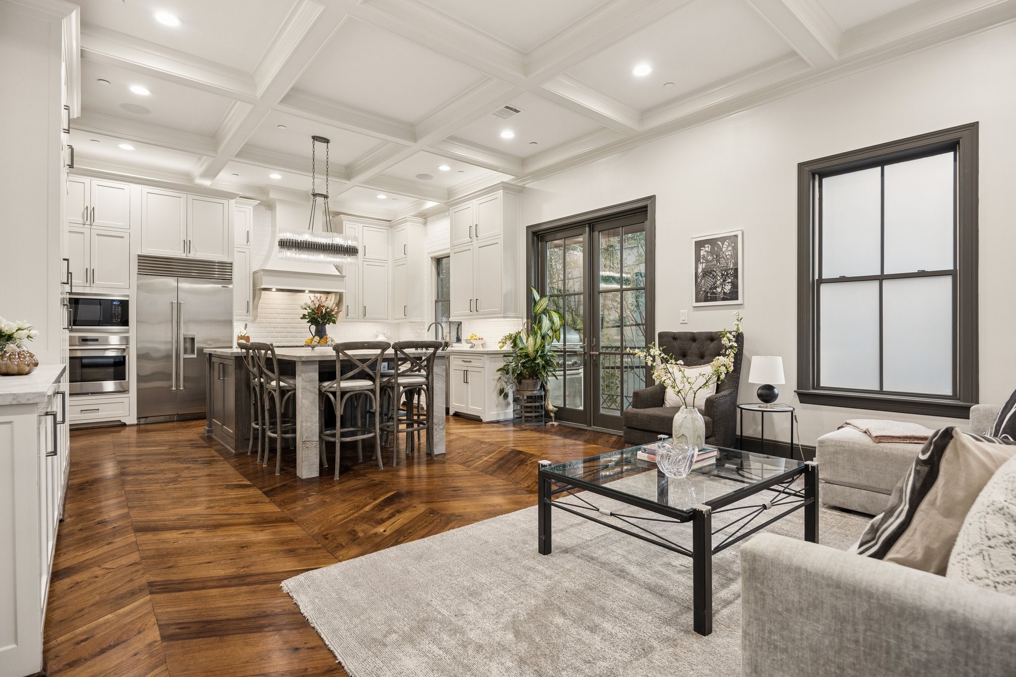 Beautiful open-concept living and kitchen area with French doors opening to a private outdoor patio featuring a gas grillperfect for effortless indoor-outdoor entertaining.