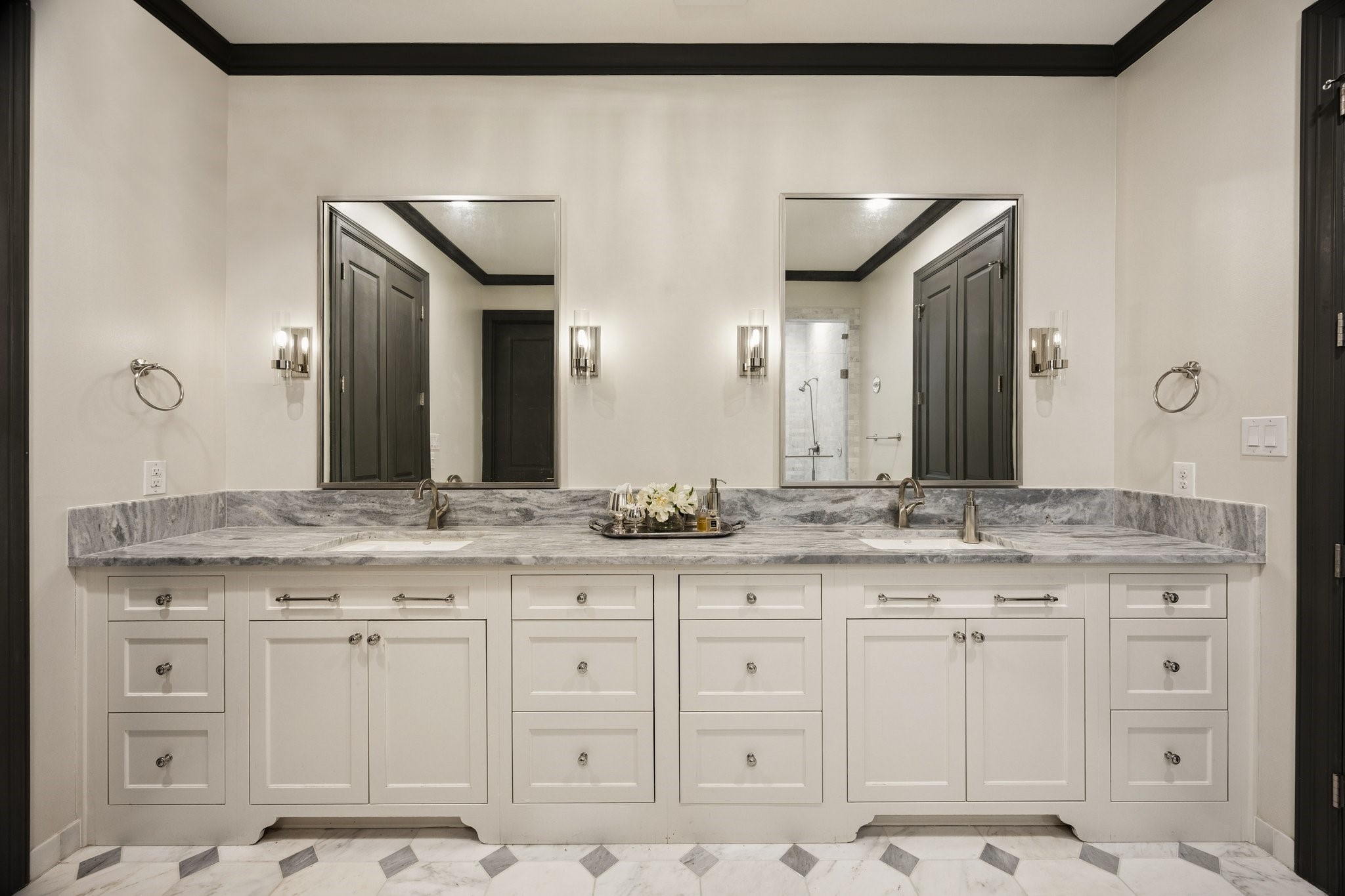 Beautifully designed double vanity with elegant marble countertops, custom cabinetry offering generous storage, and dual sinks.