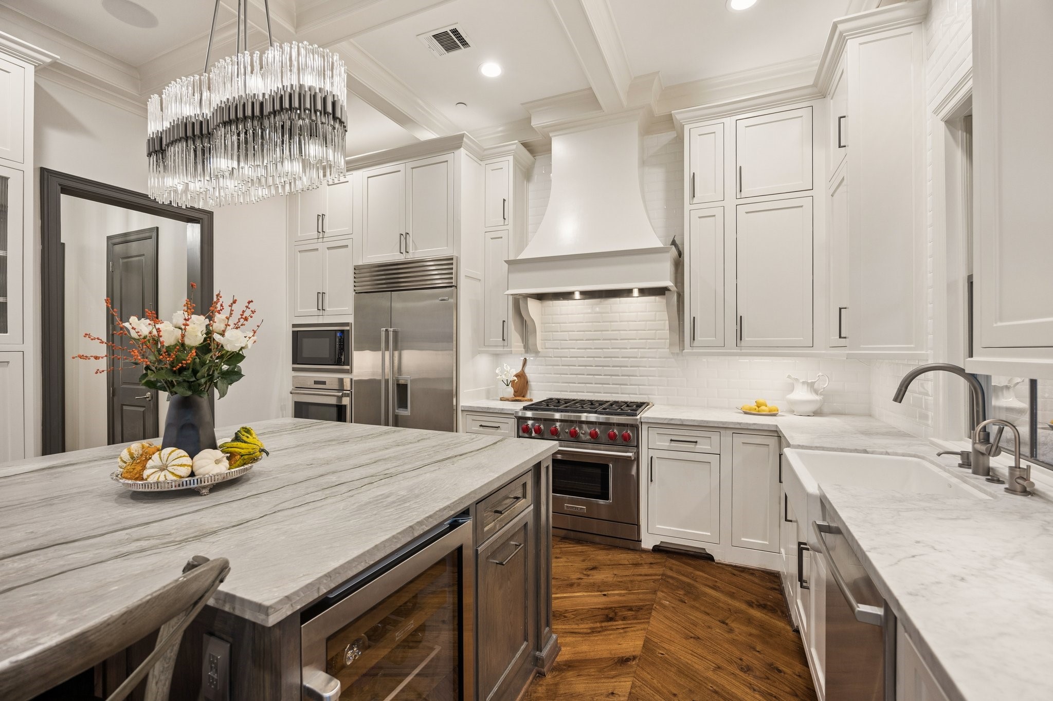 Beautifully appointed kitchen featuring a professional-grade Wolf gas range, custom vent hood, farmhouse sink, elegant coffered ceiling, and exquisite craftsmanship throughout. Beautifully appointed kitchen featuring a professional-grade Wolf gas range, custom vent hood, farmhouse sink, elegant coffered ceiling, and exquisite craftsmanship throughout.