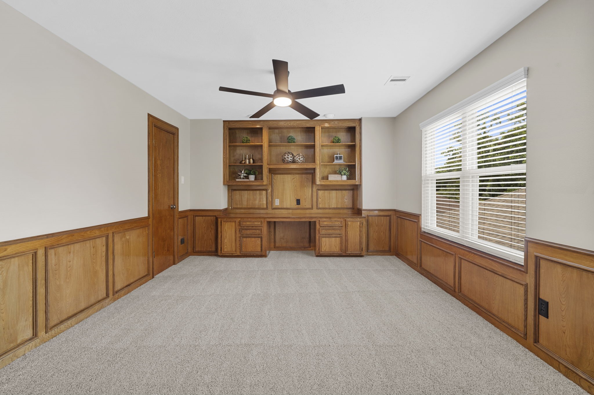 A spacious private study features extensive custom wood built-ins, cabinetry & rich millwork, creating a handsome and functional workspace.