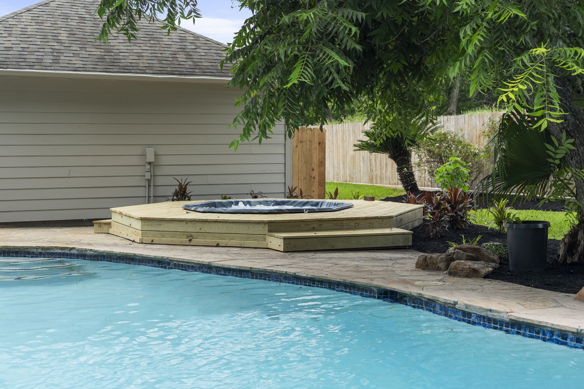 A separate hot tub with a newly built surround creates its own dedicated space just steps from the pool.