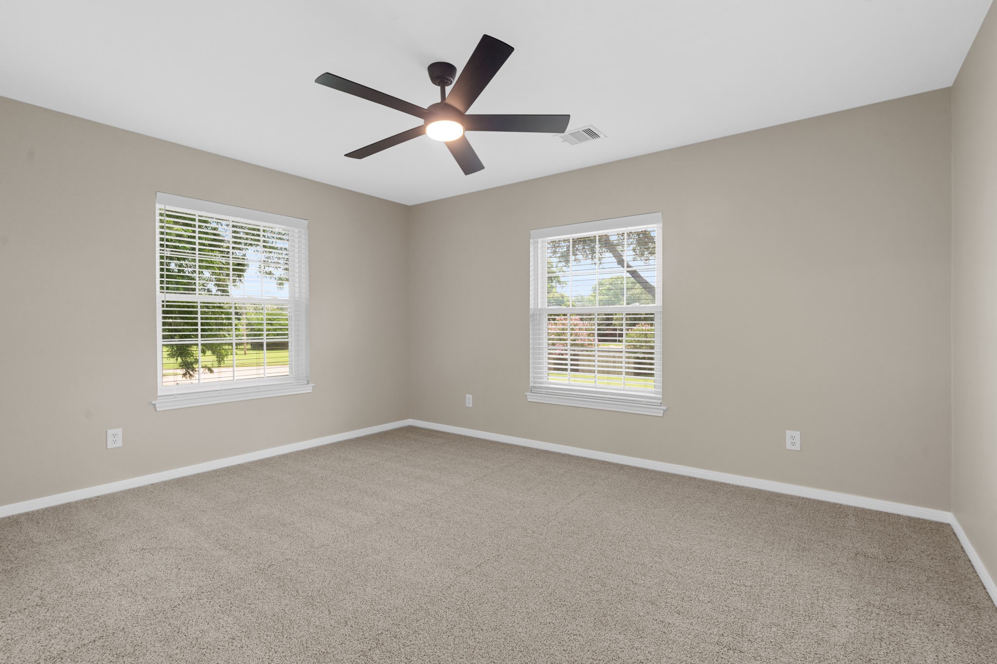 A spacious secondary bedroom is filled with natural light from dual windows and offers plenty of room for a comfortable sitting or study area.