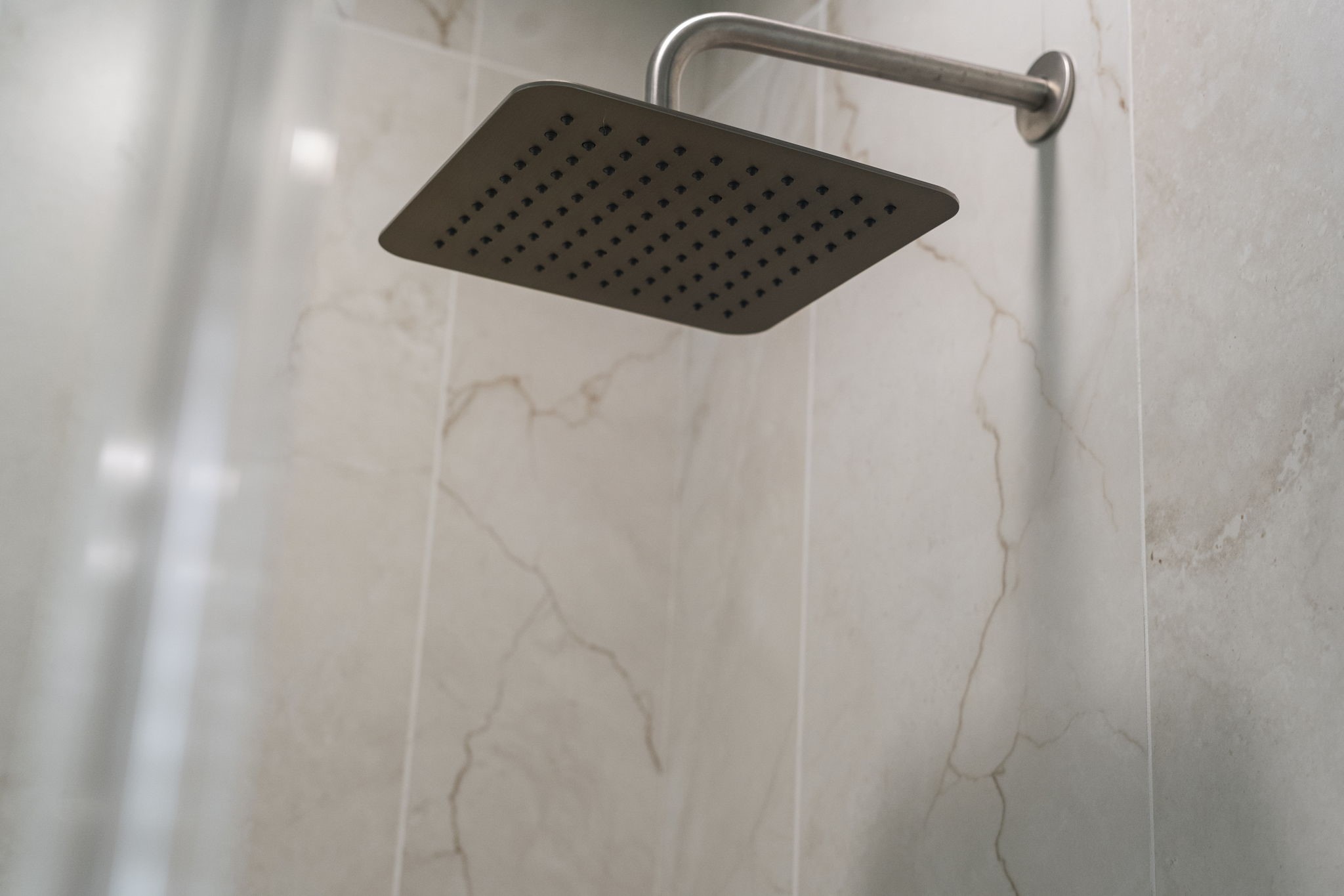 An oversized rain shower head adds a luxurious finishing touch to the beautifully tiled primary shower. An oversized rain shower head adds a luxurious finishing touch to the beautifully tiled primary shower.