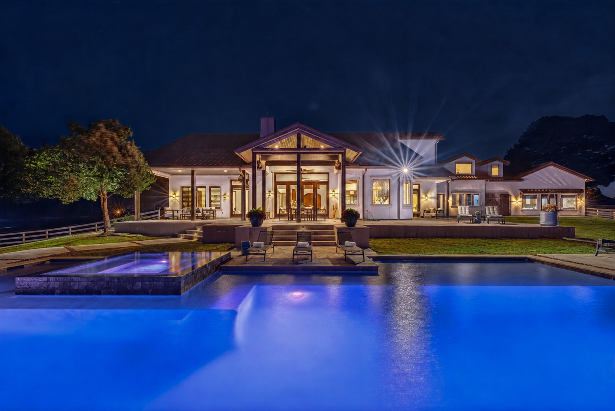 As twilight falls, the illuminated pool transforms home into an unforgettable evening destination.