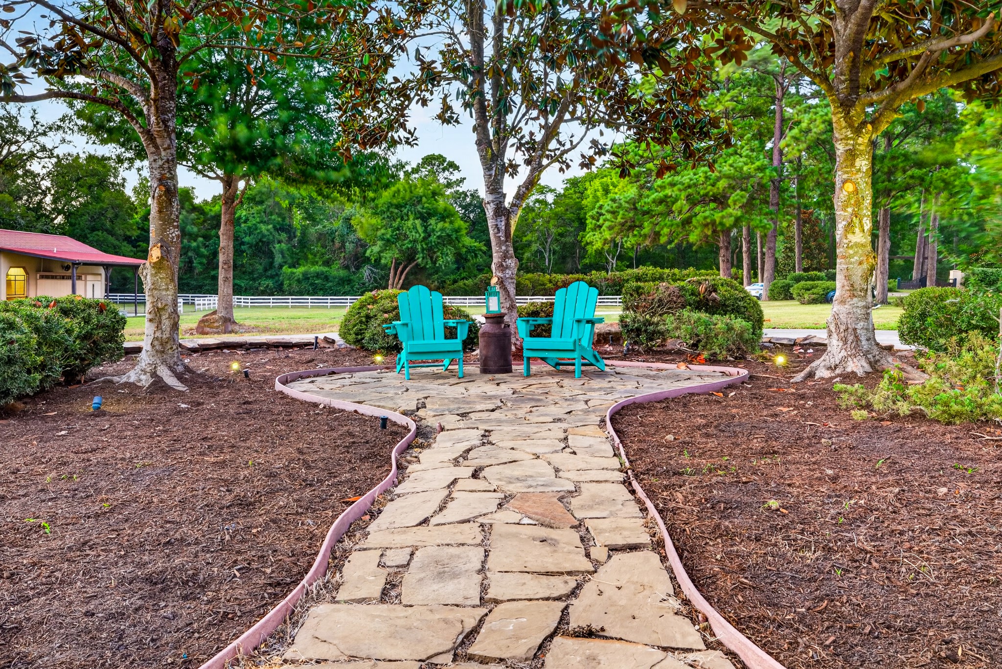 Beneath the oaks, two blue chairs invite conversation, stillness and an unhurried afternoon.