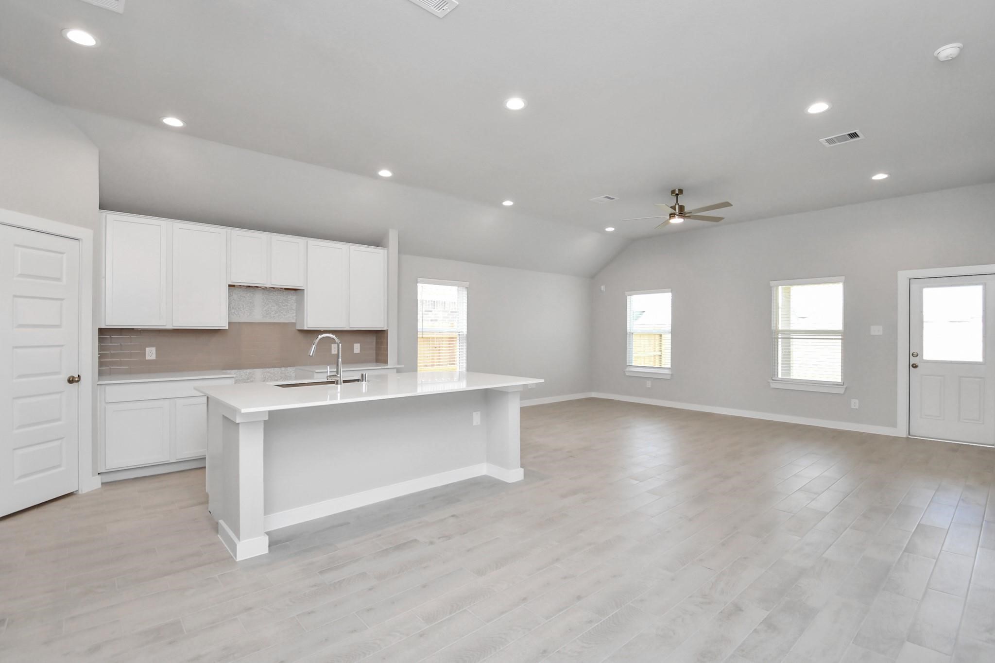 Spacious kitchen with large island, granite countertops,  and white cabinets,