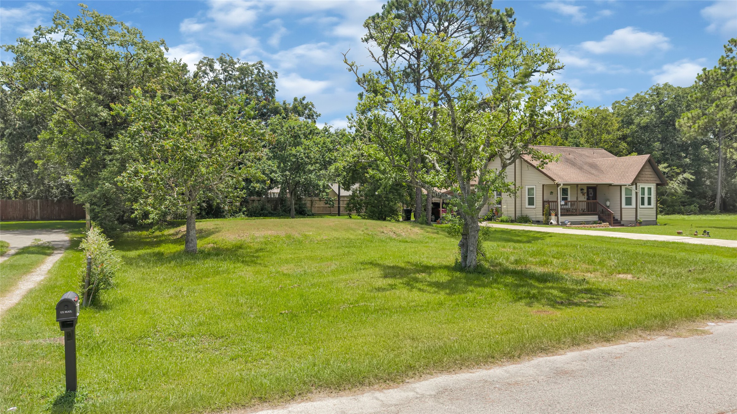 Charming single-story home nestled on a spacious, lush green lot with mature trees, offering ample outdoor space and privacy.