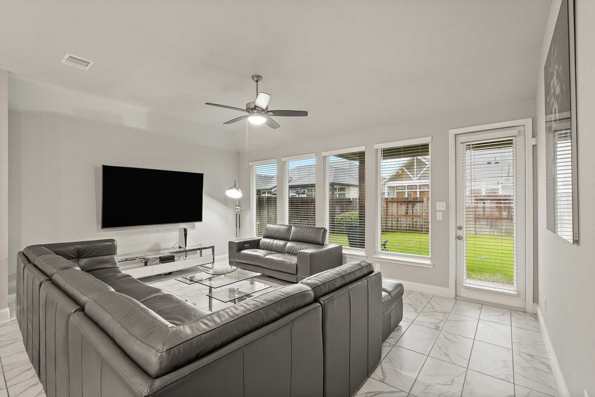 An open and inviting living room boasting premium marble-look tile floors, tall windows for abundant natural light, a recessed ceiling with a modern fan. An open and inviting living room boasting premium marble-look tile floors, tall windows for abundant natural light, a recessed ceiling with a modern fan.