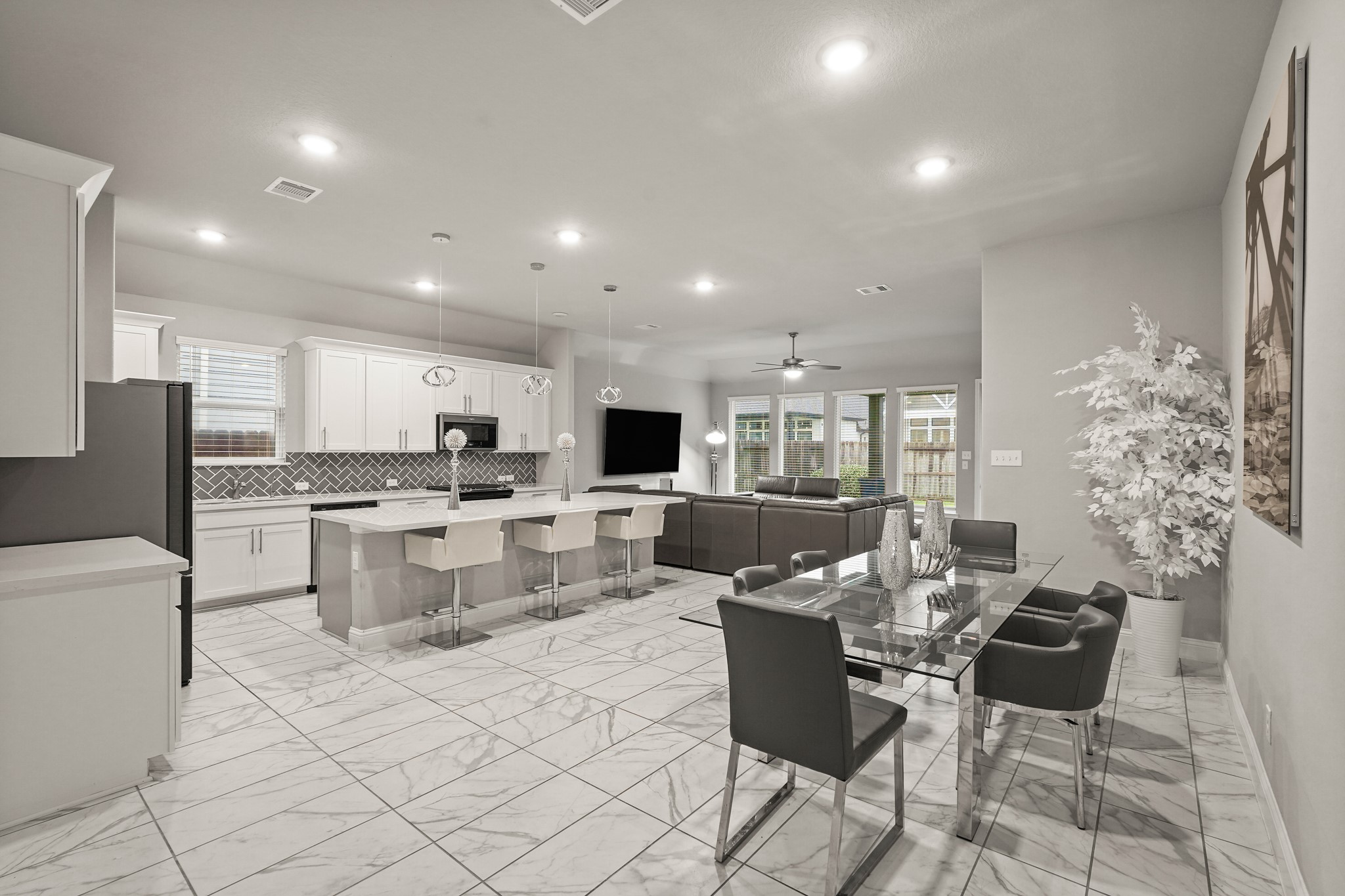 A wide-angle view of the open-concept main floor, highlighting a modern kitchen with a massive island, and a spacious dining area. A wide-angle view of the open-concept main floor, highlighting a modern kitchen with a massive island, and a spacious dining area.