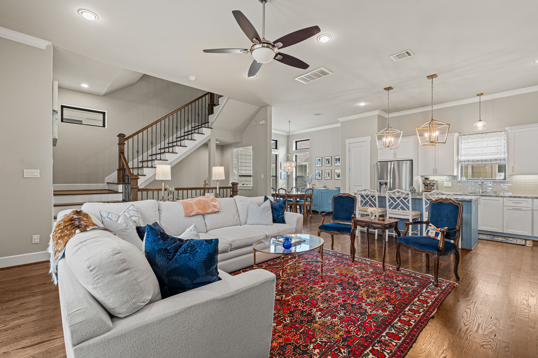 An expansive ceiling and recessed lighting frame a living space with room to breathe. The kitchen remains part of the scene, inviting an easy rhythm between hosting and relaxing.