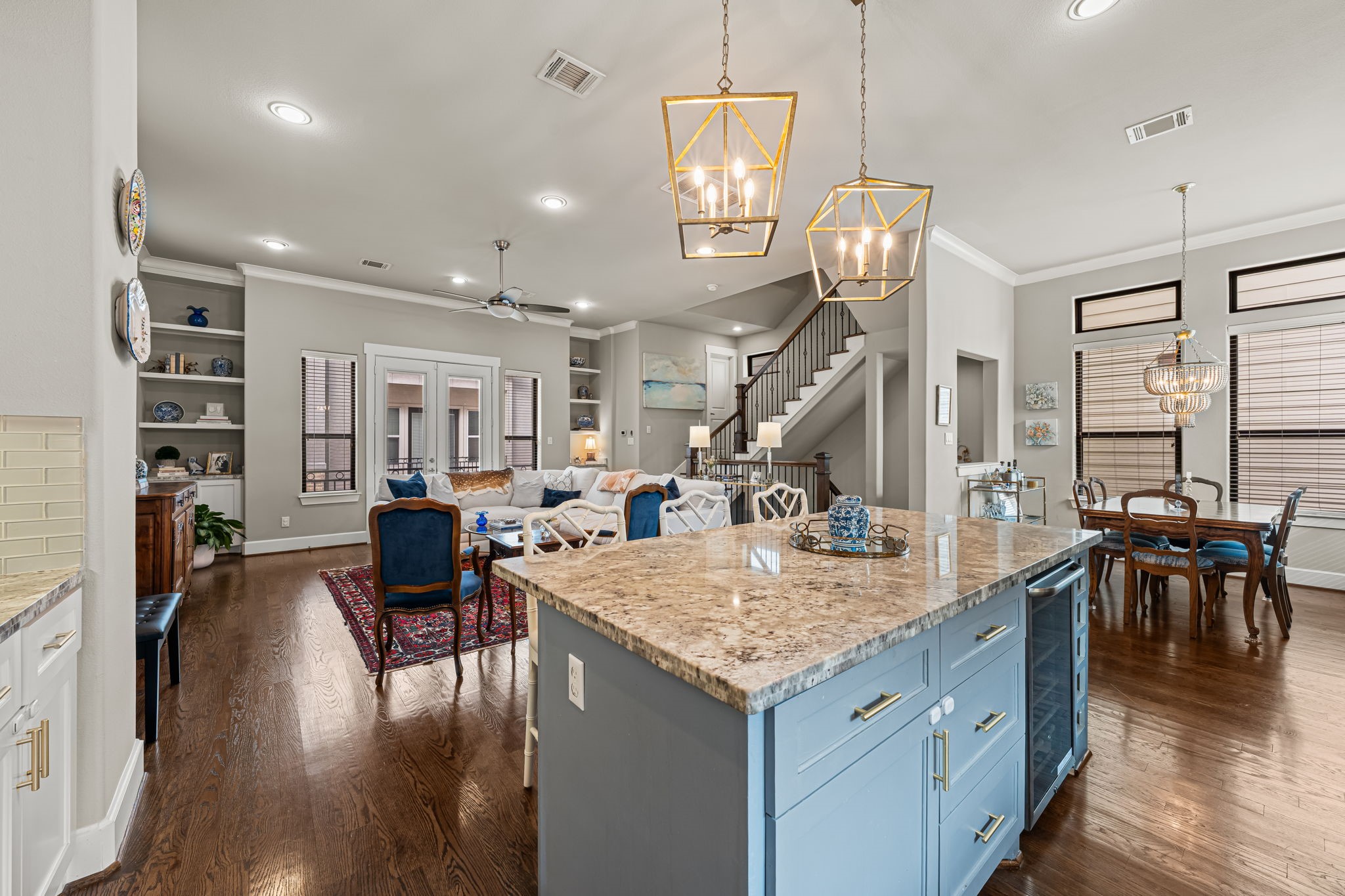 The substantial island anchors the room with a broad preparation surface and a richly colored base. Clear pathways connect cooking, dining, and gathering without interrupting the flow.