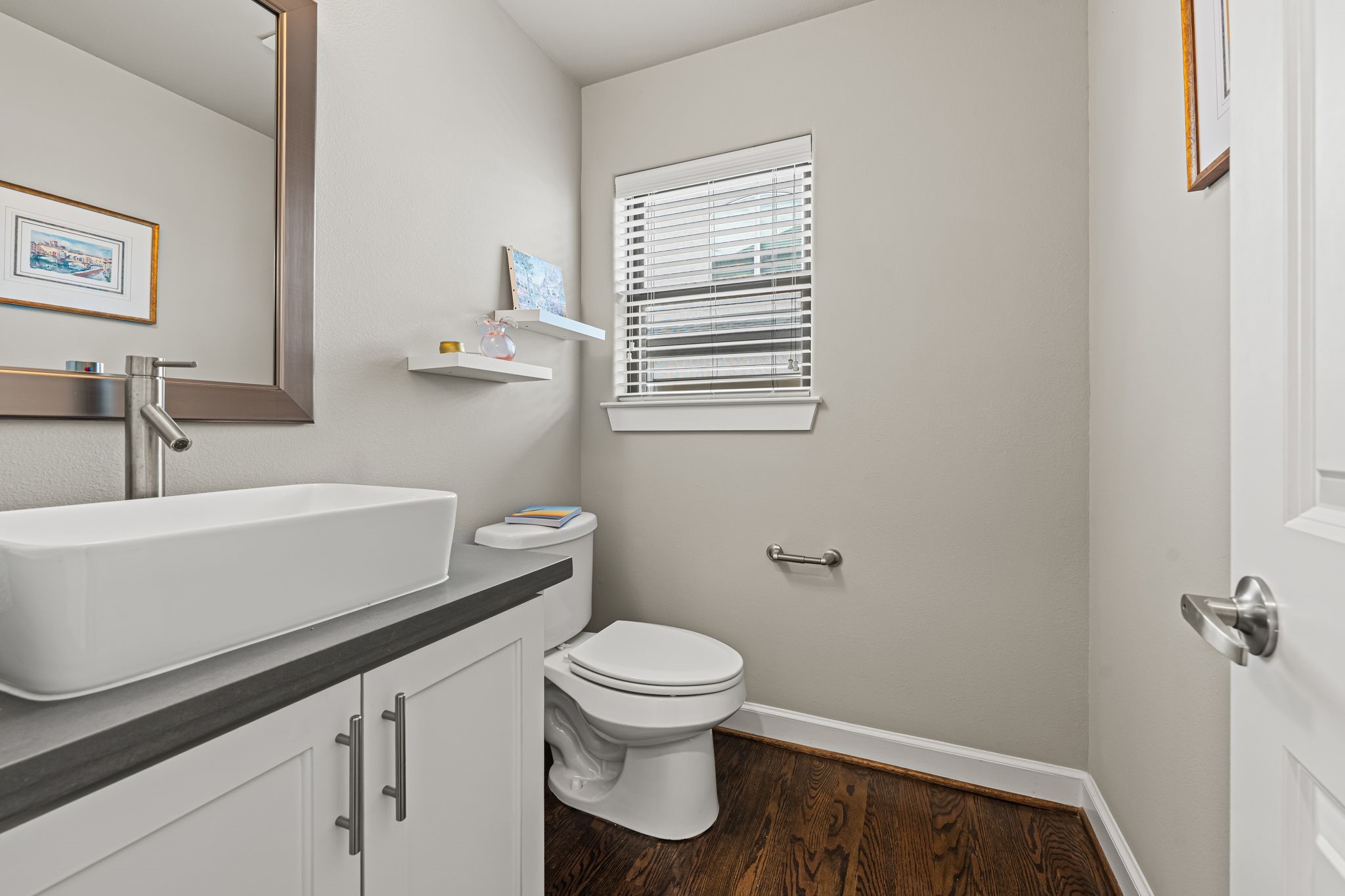 A rectangular vessel sink brings a sculptural touch to the powder room. Clean lines and a restrained palette create a polished space for guests to refresh.