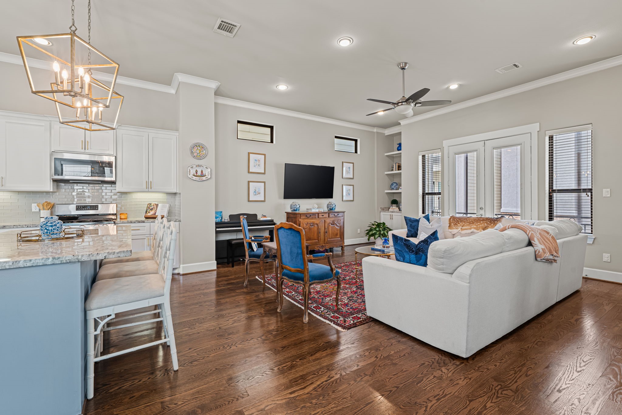 From the kitchen, the view opens toward a generous living area washed in daylight. A continuous sweep of hardwoods ties the spaces together with warmth and ease.