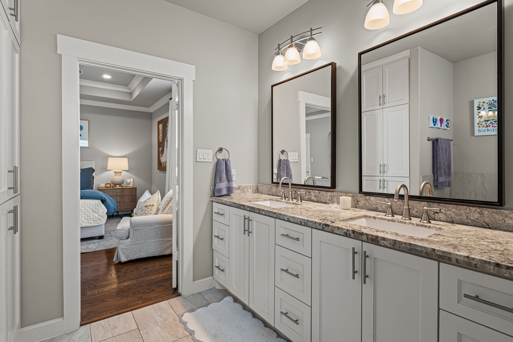 Framed mirrors and gleaming fixtures bring a tailored finish to the primary vanity. An extended counter and plentiful drawers keep daily essentials neatly organized.